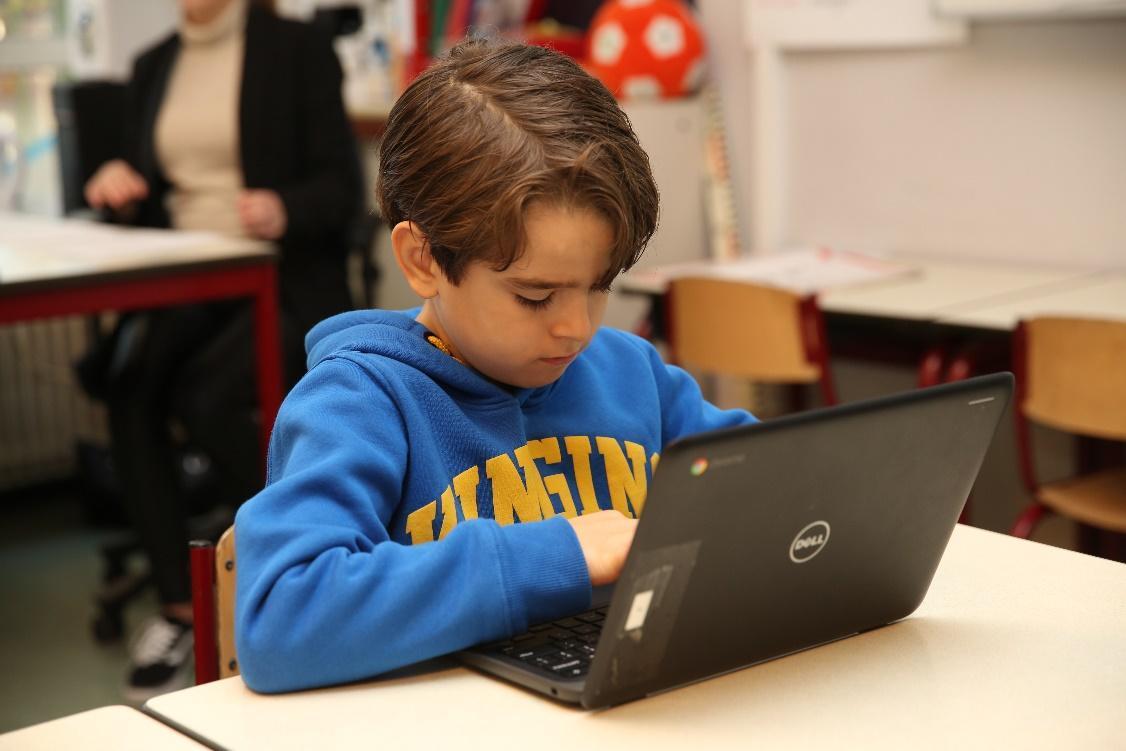 Een jongen in een blauwe hoodie werkt geconcentreerd aan een laptop in Basisschool De Uilenburcht in Driebergen-Rijsenburg. Een jongen in een blauwe hoodie werkt geconcentreerd aan een laptop in Basisschool De Uilenburcht in Driebergen-Rijsenburg.