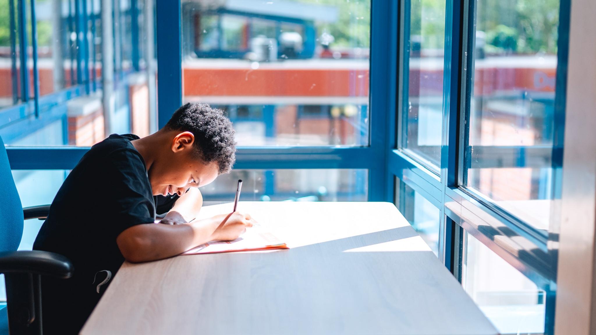 Een jongen maakt aantekeningen aan een tafel in Basisschool De Horizon in Delft. Een jongen maakt aantekeningen aan een tafel in Basisschool De Horizon in Delft.