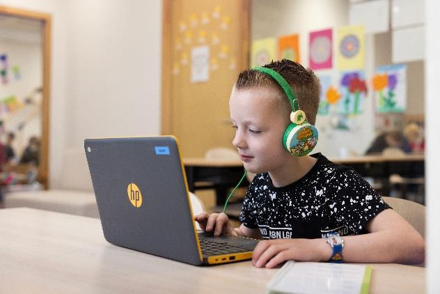 Een jongen met een laptop en hoofdtelefoon aan het leren in de klas van 't PuzzelsTuk in Tuk. Een jongen met een laptop en hoofdtelefoon aan het leren in de klas van 't PuzzelsTuk in Tuk.