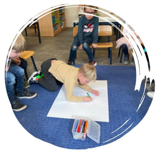 Een jongen schrijft op een groot vel papier terwijl andere kinderen toekijken in de RK Basisschool Sint Jozef in Someren. Een jongen schrijft op een groot vel papier terwijl andere kinderen toekijken in de RK Basisschool Sint Jozef in Someren.