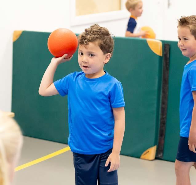 Een jongen speelt met een oranje bal tijdens de gymles op Christelijke Basisschool De Bron in Wezep.