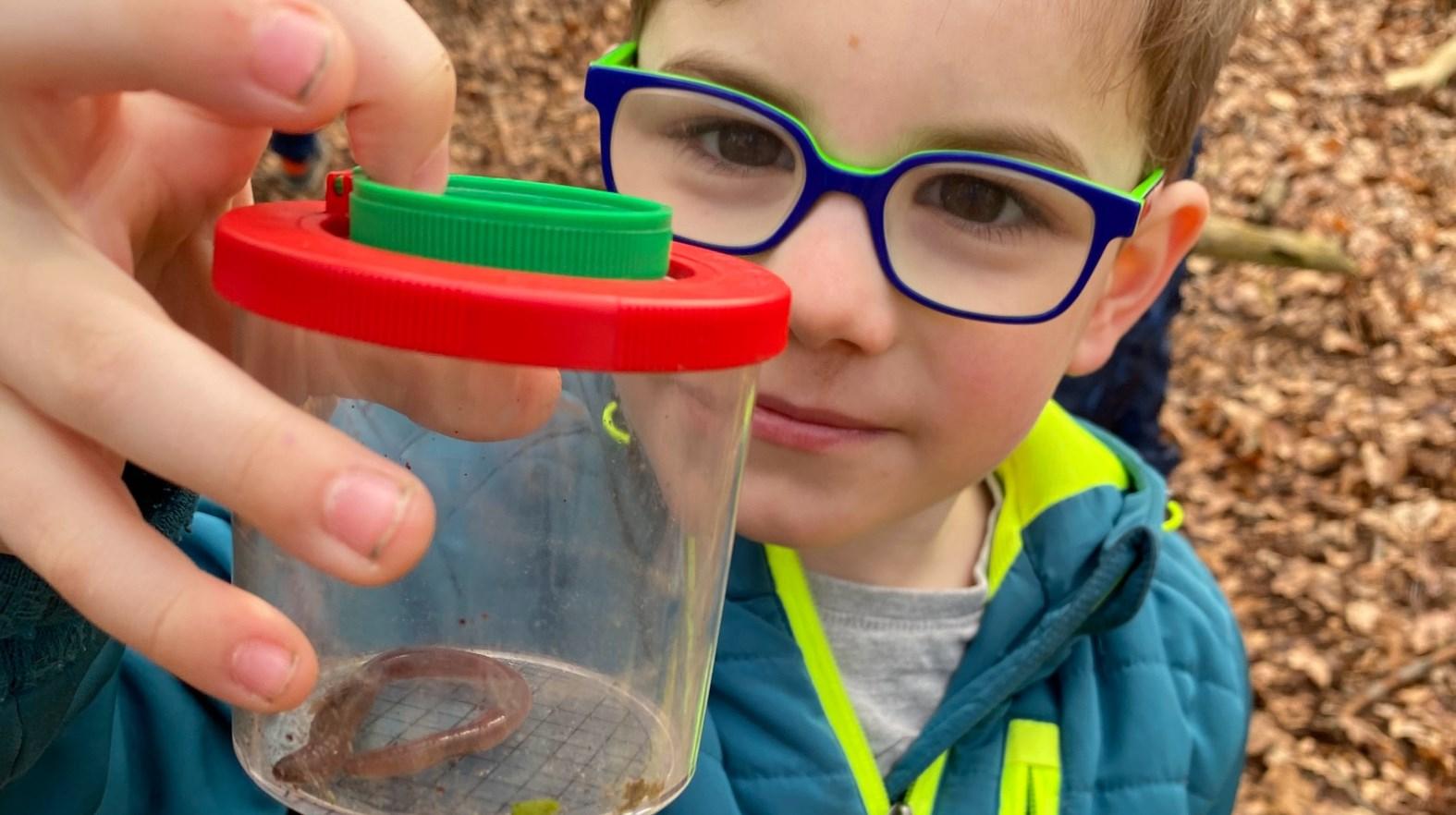 Een jongen van Basisschool Hulsberg houdt een doorzichtig opvangbakje met een worm vast tijdens een buitenactiviteit. Een jongen van Basisschool Hulsberg houdt een doorzichtig opvangbakje met een worm vast tijdens een buitenactiviteit.