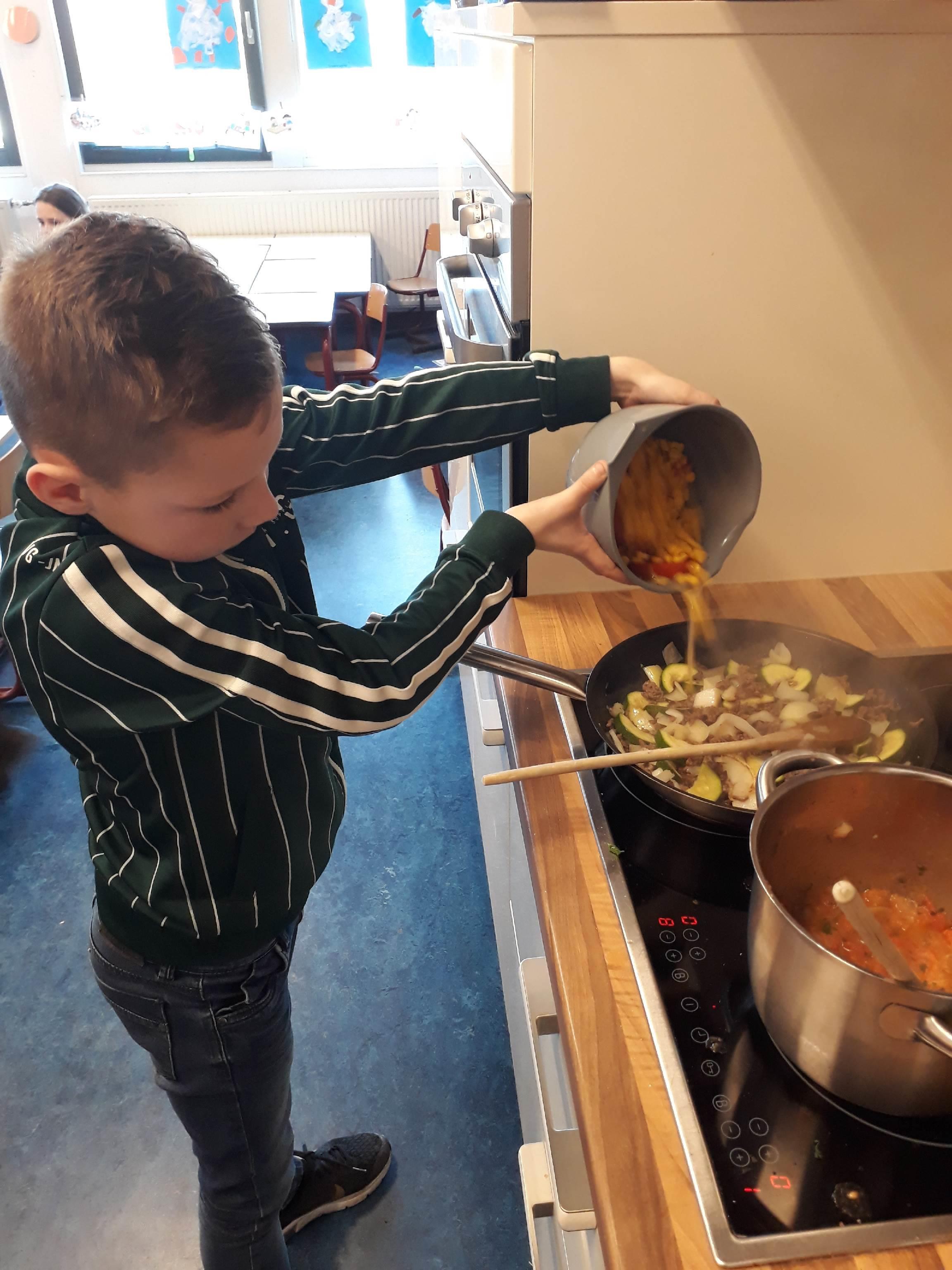 Een jongen van KC 't Echtenest in Echten (Drenthe) voegt groenten toe aan een pan terwijl hij aan het koken is. Een jongen van KC 't Echtenest in Echten (Drenthe) voegt groenten toe aan een pan terwijl hij aan het koken is.