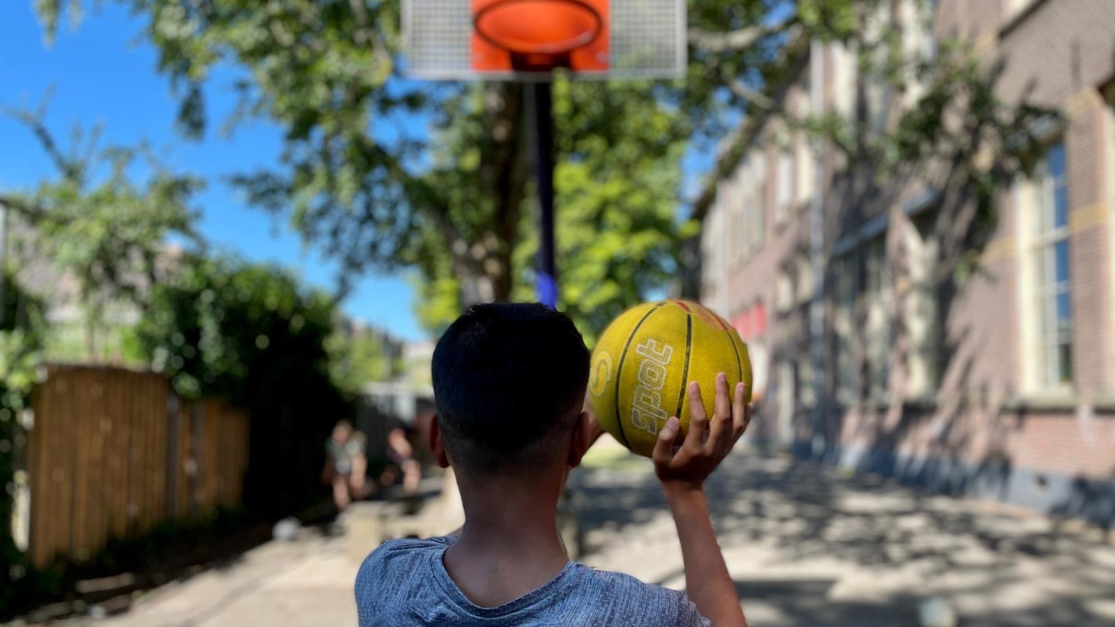 Een jongen werpt een gele basketbal op het schoolplein van IKC Borgman Oosterpoort in Groningen. Een jongen werpt een gele basketbal op het schoolplein van IKC Borgman Oosterpoort in Groningen.