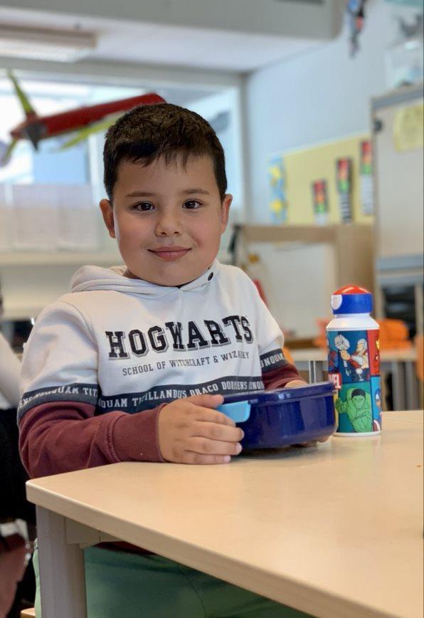 Een jongen zit aan een tafel in de Prinses Marijkeschool in Den Haag met een blauwe kom en een drinkfles. Een jongen zit aan een tafel in de Prinses Marijkeschool in Den Haag met een blauwe kom en een drinkfles.