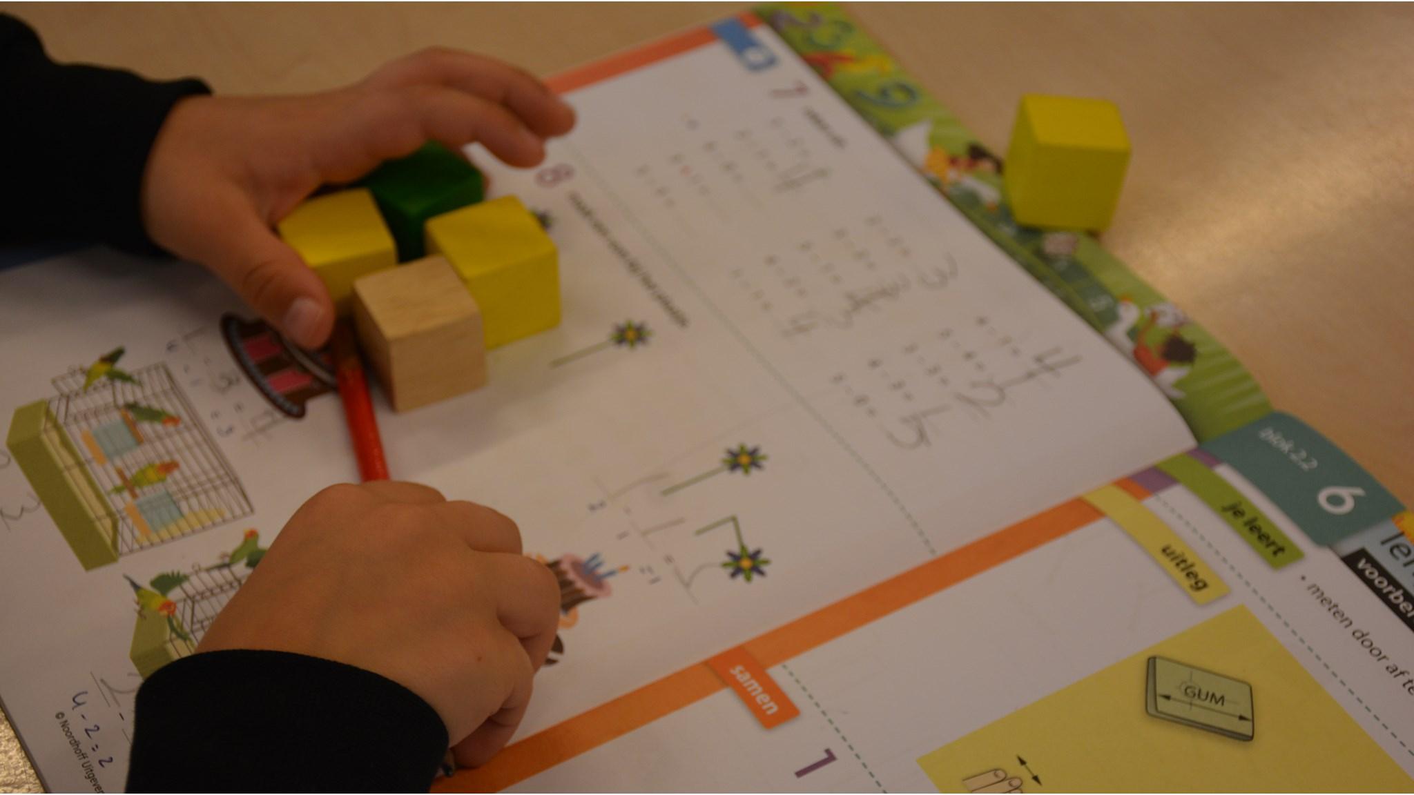 Een kind aan het werk met blokken en een werkboek op Openbare Basisschool De Kweekvijver in Oostzaan.
