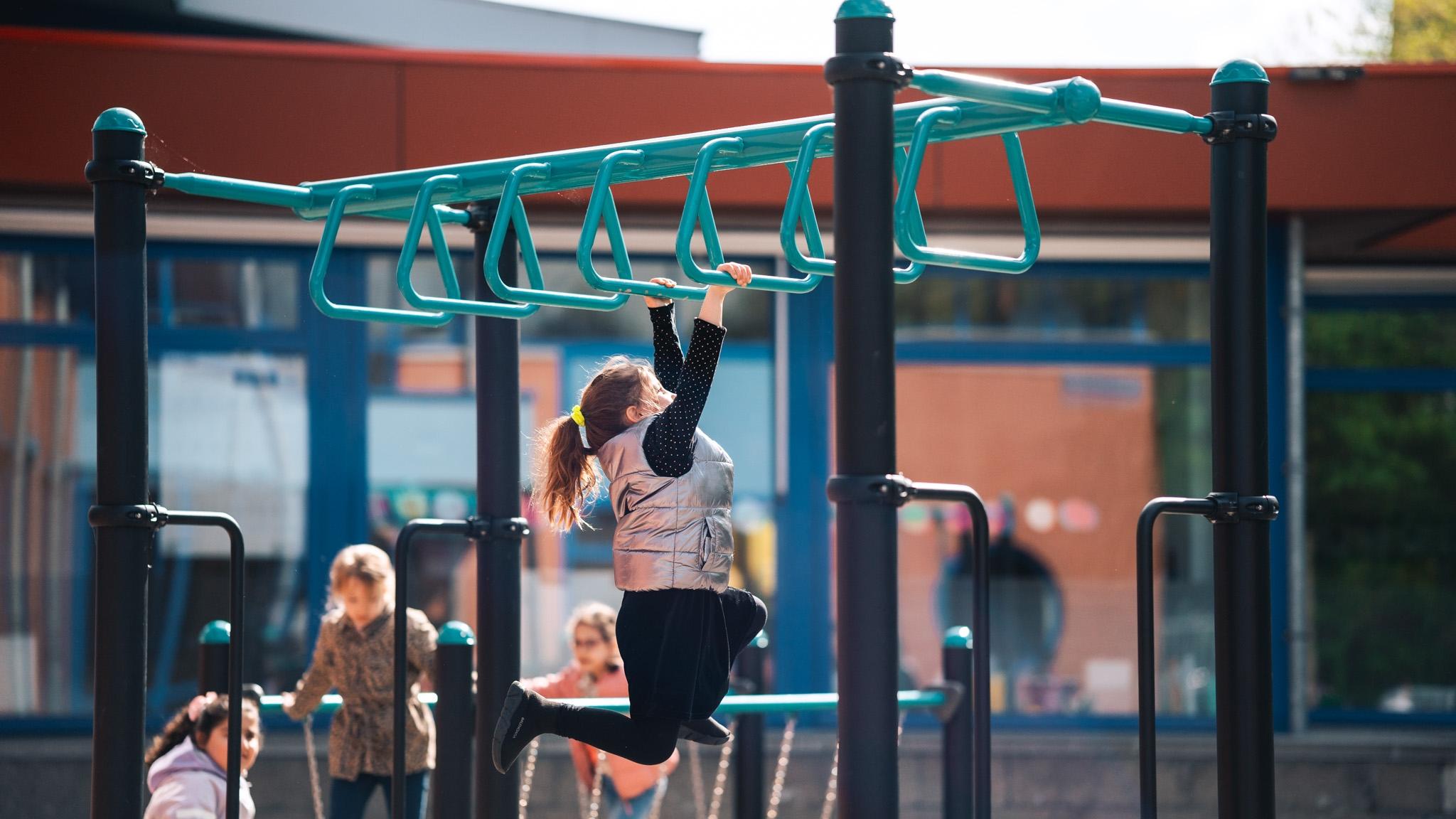Een kind hangt aan de speeltuin klimrekken op het schoolplein van Basisschool De Horizon in Delft. Een kind hangt aan de speeltuin klimrekken op het schoolplein van Basisschool De Horizon in Delft.