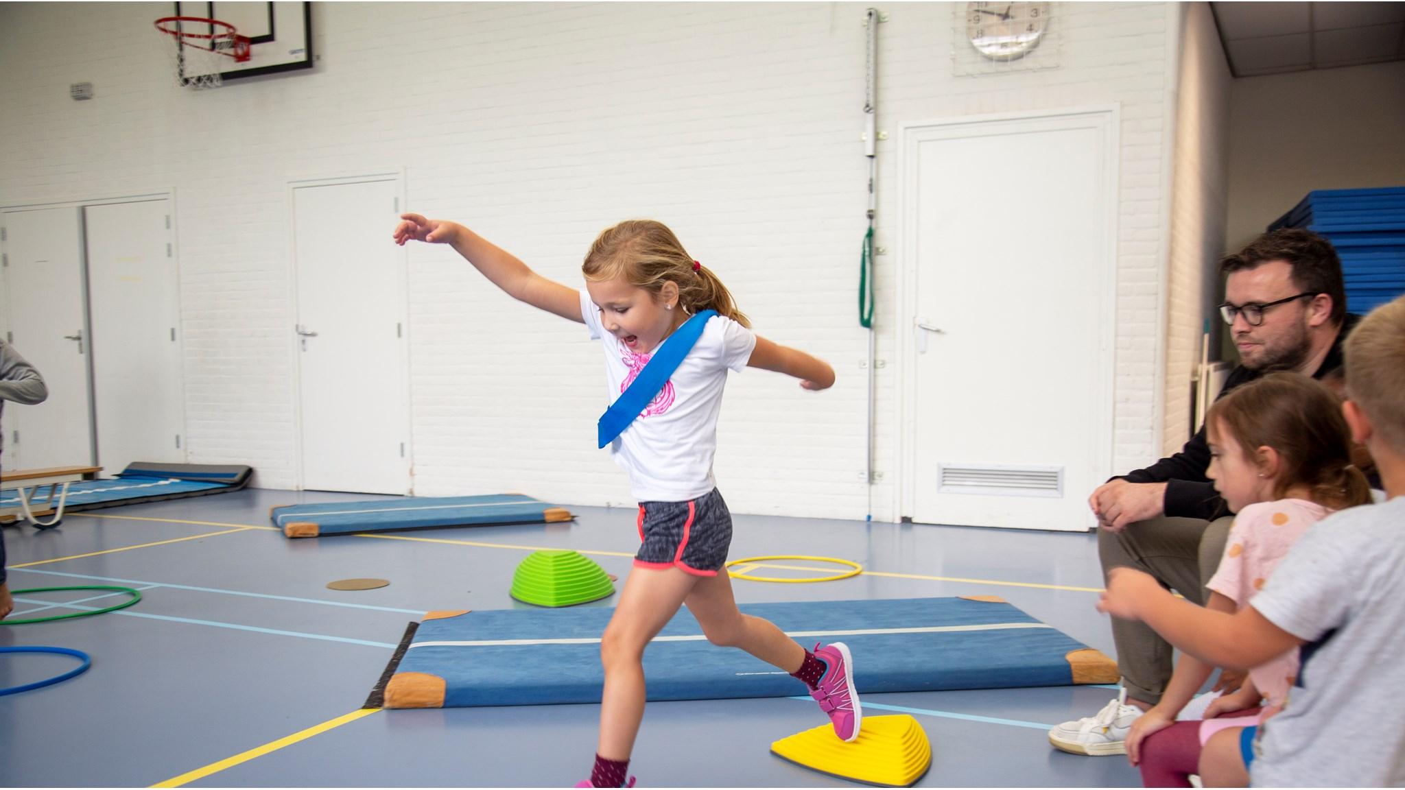 Een kind in de gymzaal van RK Basisschool Holtkamp in Goes balanceert enthousiast over geïmproviseerde obstakels. Een kind in de gymzaal van RK Basisschool Holtkamp in Goes balanceert enthousiast over geïmproviseerde obstakels.