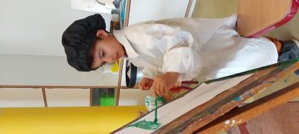 Een kind in een schilderoutfit aan het werk in de klas van De Kleine Wereld in Den Haag. Een kind in een schilderoutfit aan het werk in de klas van De Kleine Wereld in Den Haag.