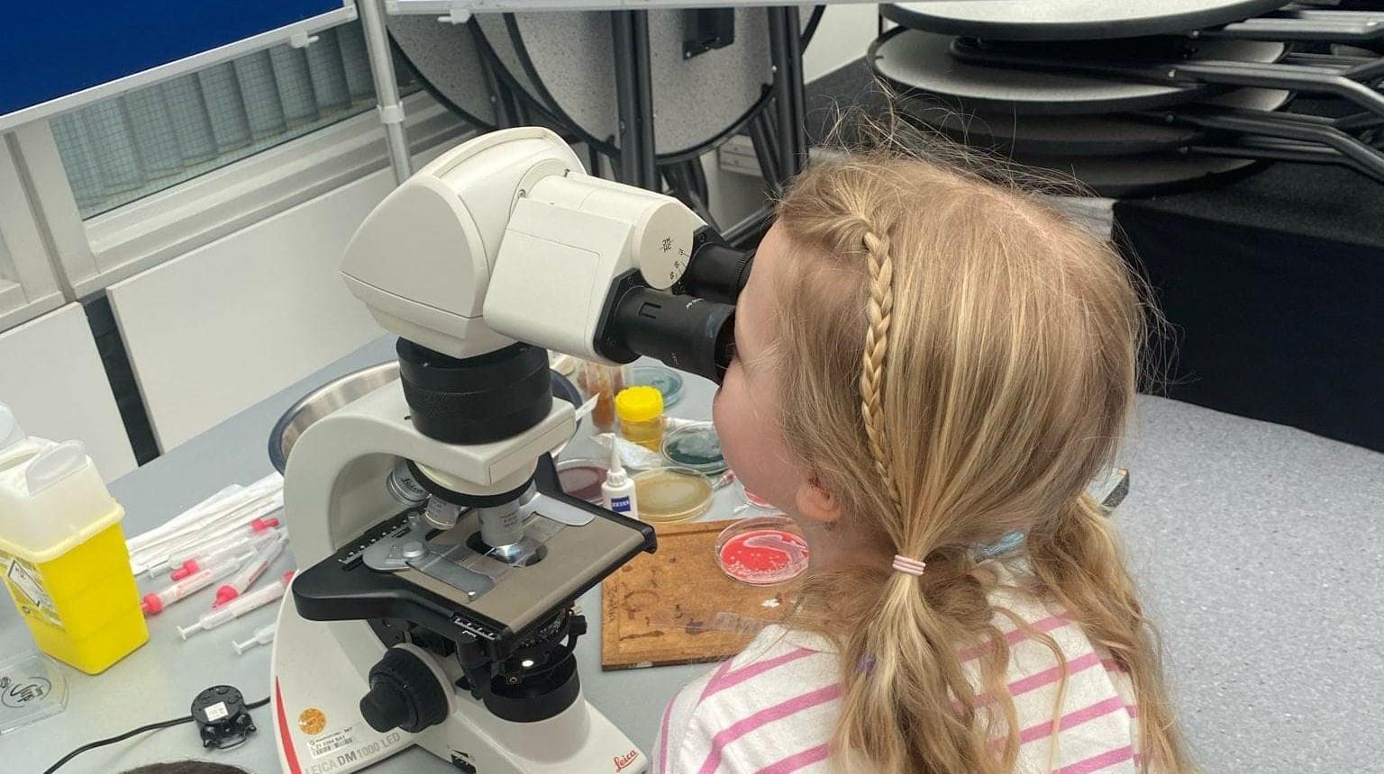 Een kind kijkt door een microscoop tijdens een les aan Basisschool De Triangel in Gulpen.
