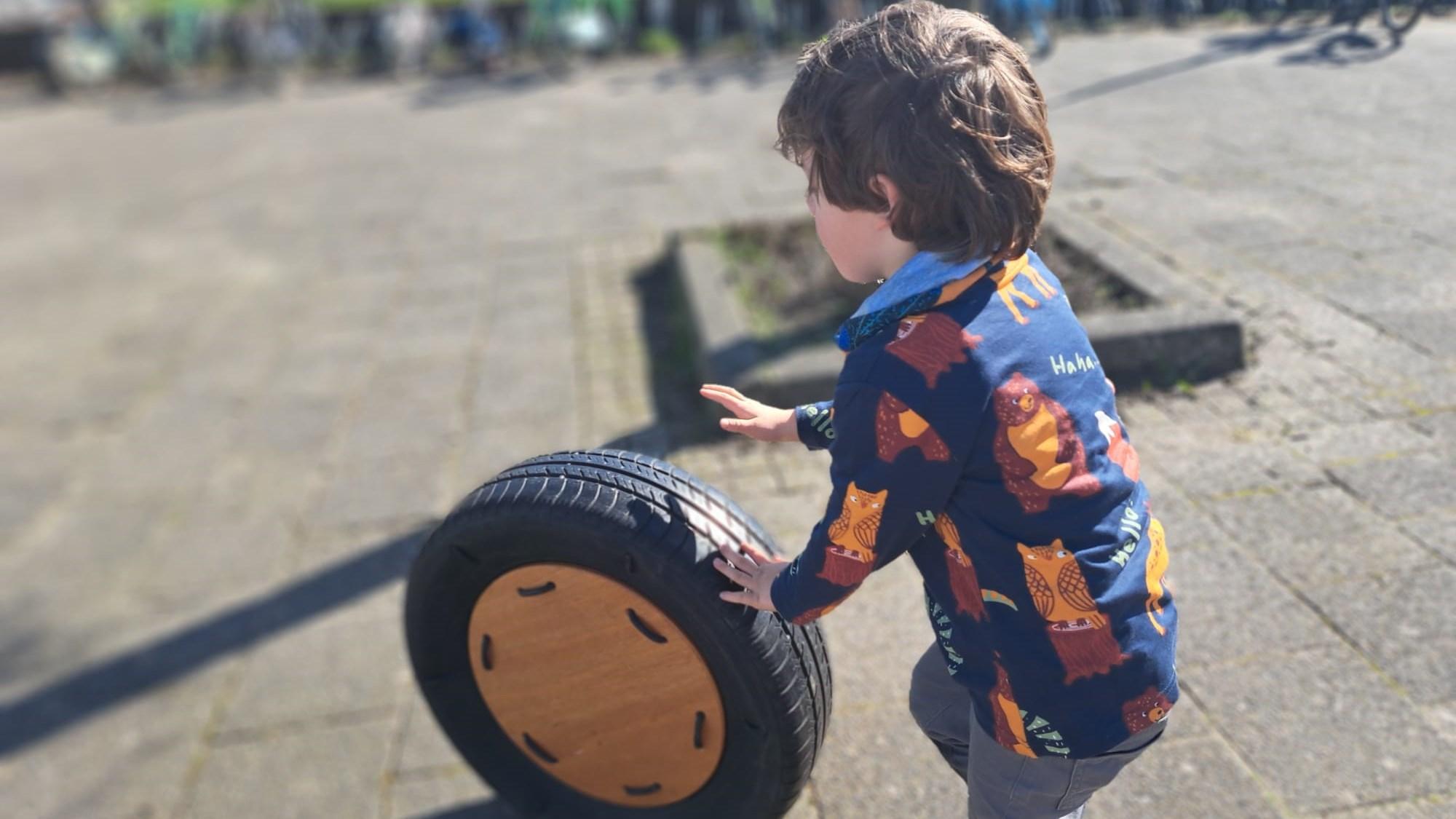 Een kind speelt met een houten wiel op het schoolplein van de Oranje Nassauschool in Dordrecht. Een kind speelt met een houten wiel op het schoolplein van de Oranje Nassauschool in Dordrecht.