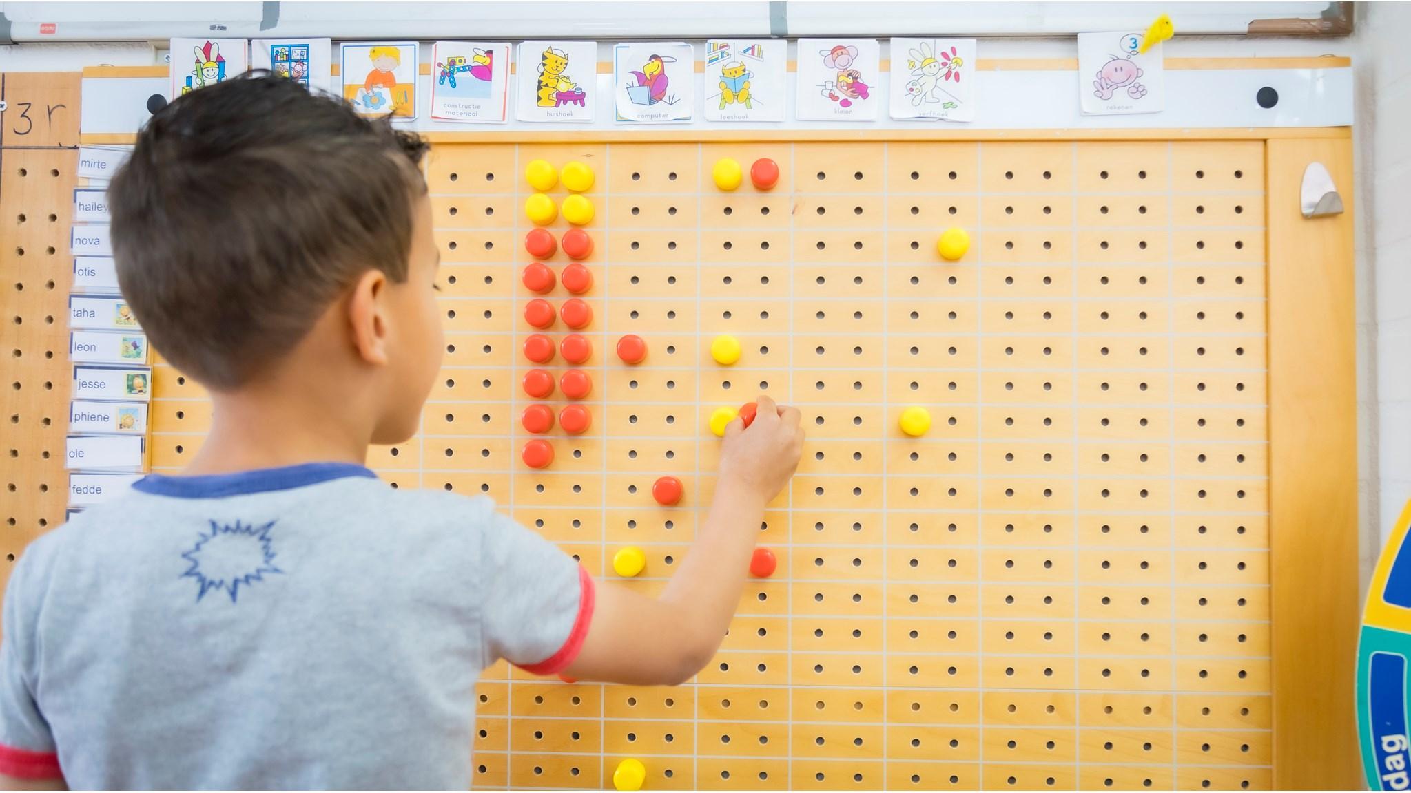 Een kind speelt met kleurencounters aan de muur in de Johan Frisoschool in Woerden. Een kind speelt met kleurencounters aan de muur in de Johan Frisoschool in Woerden.