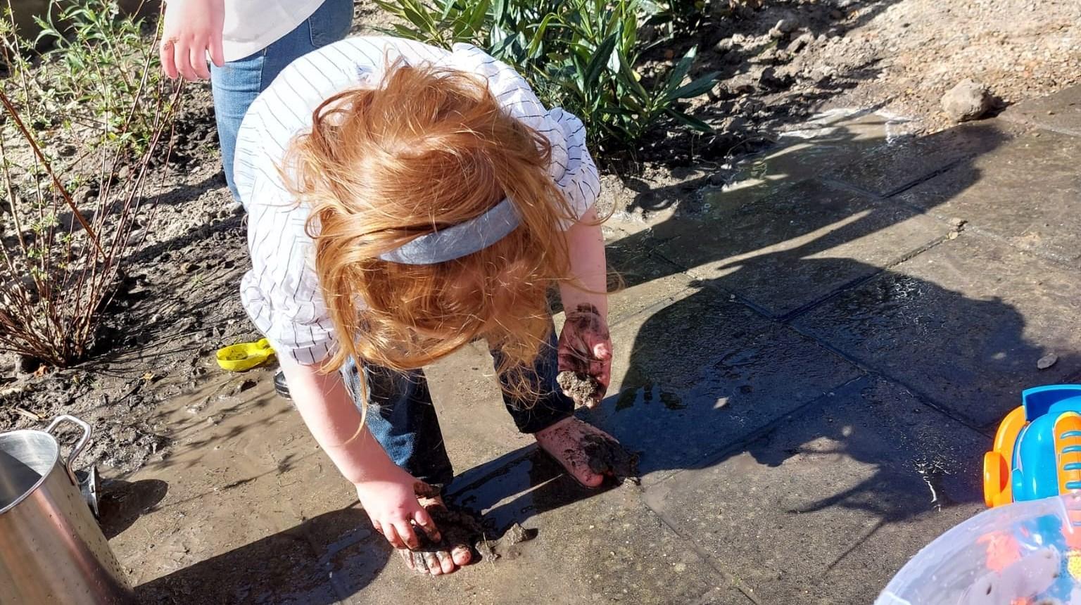 Een kind speelt met modder op het schoolplein van IKC De Stek in Est. Een kind speelt met modder op het schoolplein van IKC De Stek in Est.