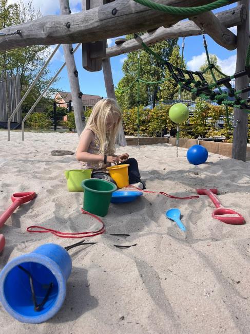 Een kind speelt met zand en speelgoed op het schoolplein van obs De Dennenkamp in Ommen. Een kind speelt met zand en speelgoed op het schoolplein van obs De Dennenkamp in Ommen.