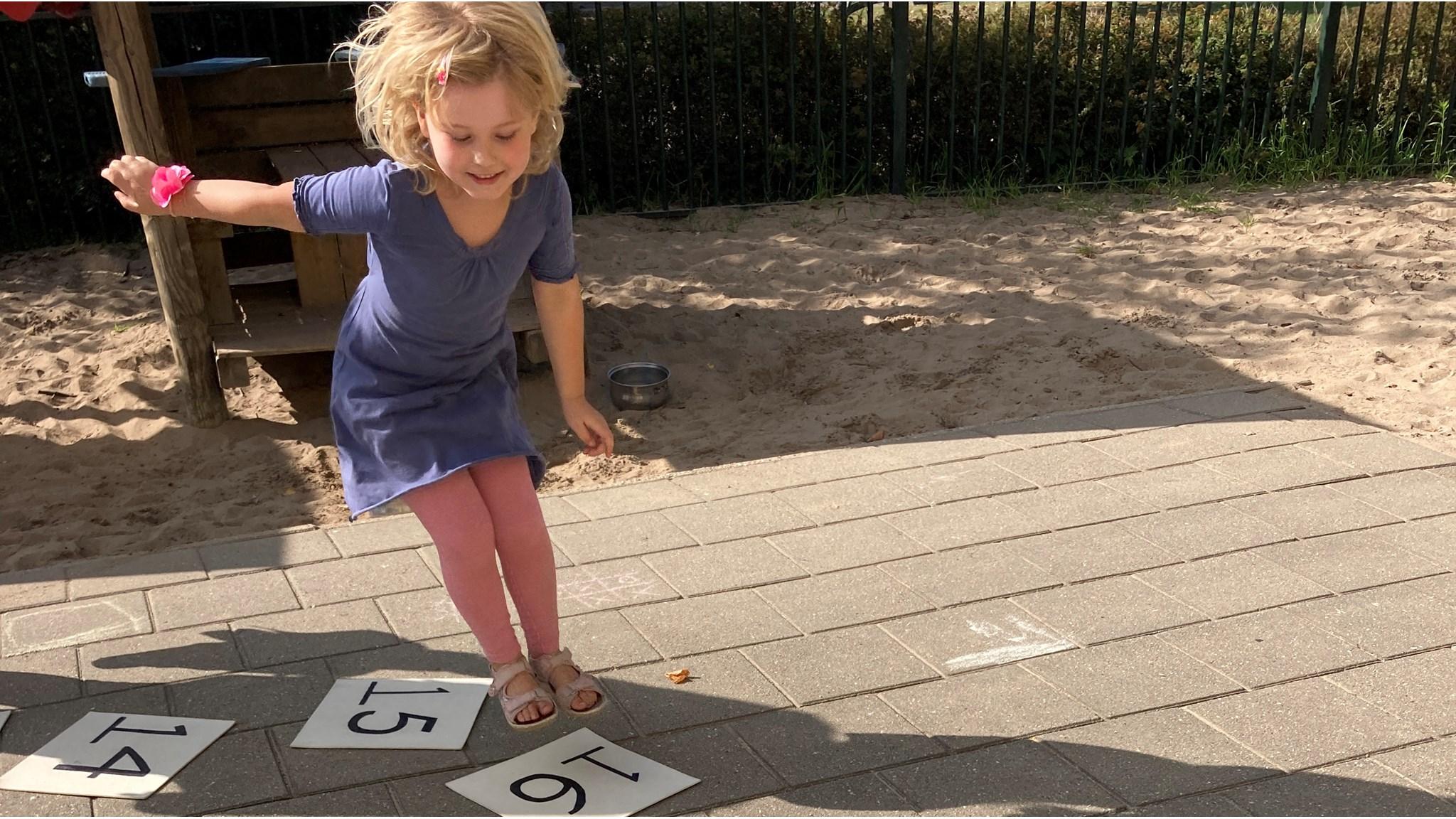 Een kind speelt op het schoolplein van De Bargeweide in Eefde met getallen op de grond. Een kind speelt op het schoolplein van De Bargeweide in Eefde met getallen op de grond.
