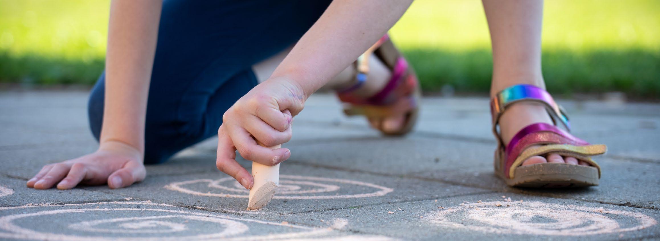 Een kind tekent met krijt op het schoolplein van de Hubertusschool in Herten. Een kind tekent met krijt op het schoolplein van de Hubertusschool in Herten.