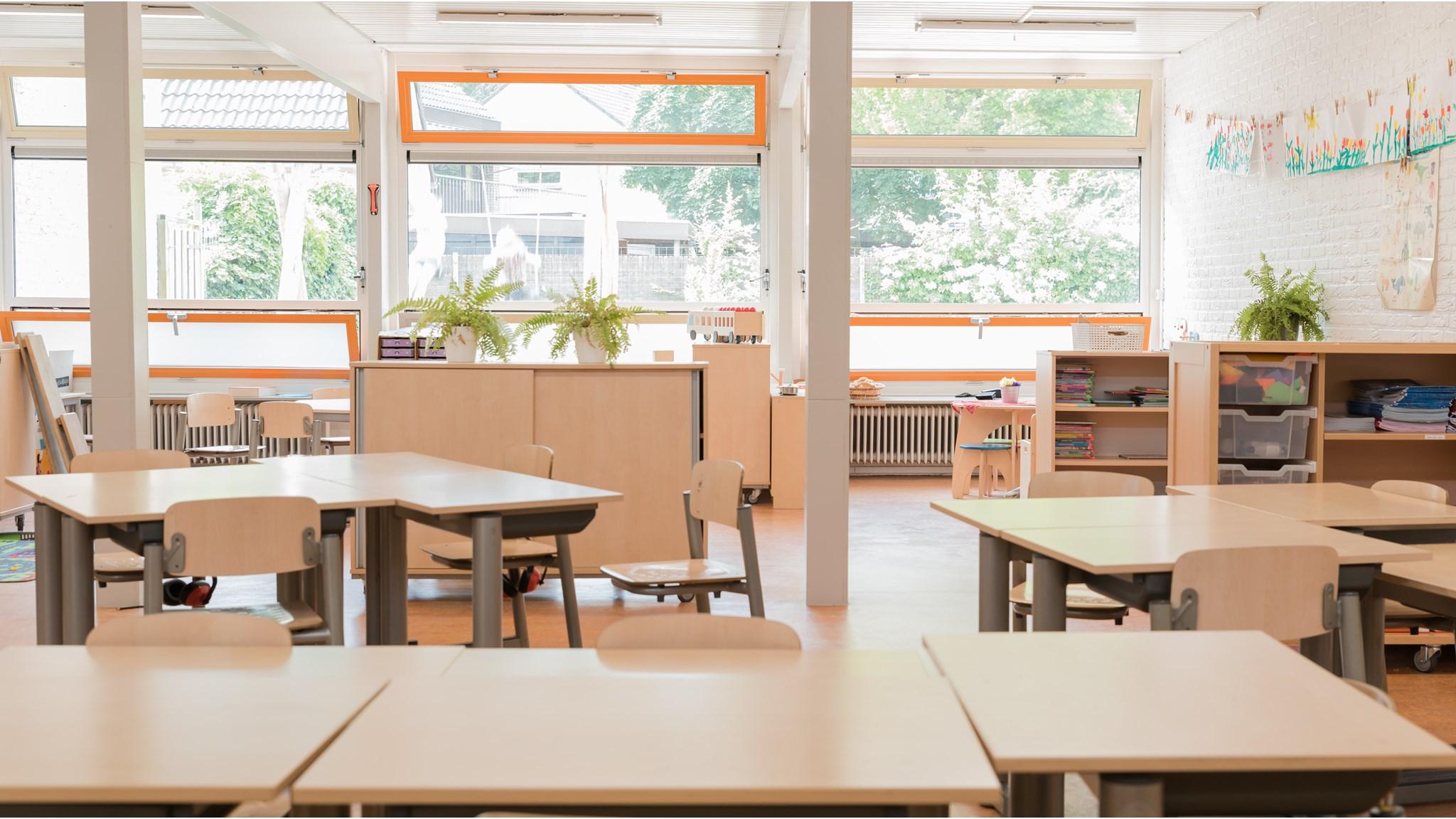 Een klaslokaal van Basisschool de Wegwijzer in Harderwijk, met houten tafels en stoelen naast grote ramen. Een klaslokaal van Basisschool de Wegwijzer in Harderwijk, met houten tafels en stoelen naast grote ramen.