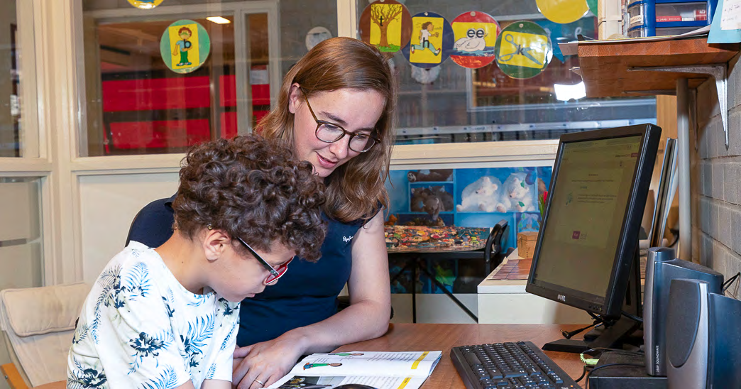 Een leerkracht en een leerling van CBS Mozaïek in Rotterdam werken samen aan een opdracht aan een bureau.