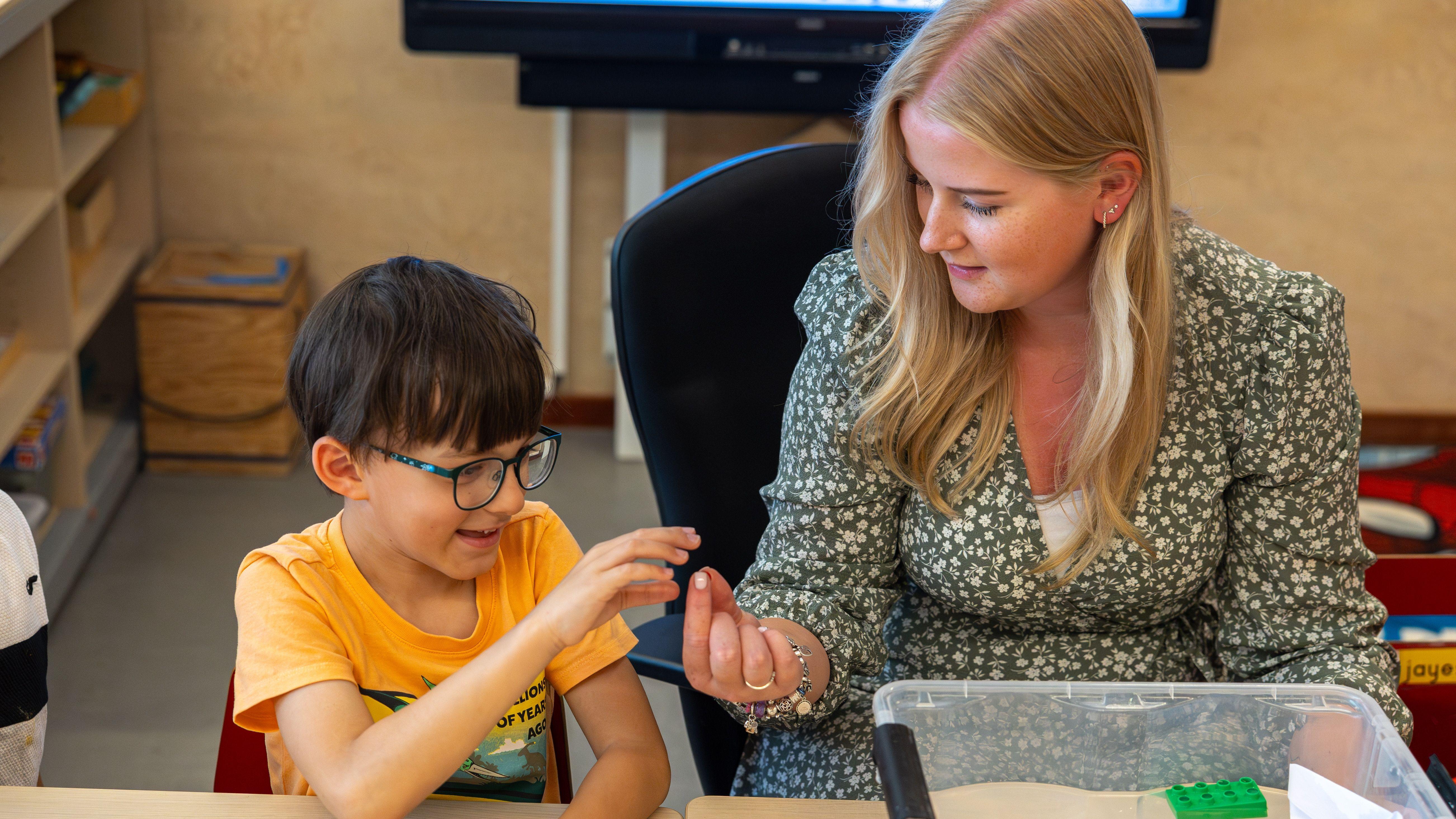 Een leerkracht en een leerling van Openbare Basisschool Syncope in Almere zijn bezig met een activiteit aan een tafel. Een leerkracht en een leerling van Openbare Basisschool Syncope in Almere zijn bezig met een activiteit aan een tafel.