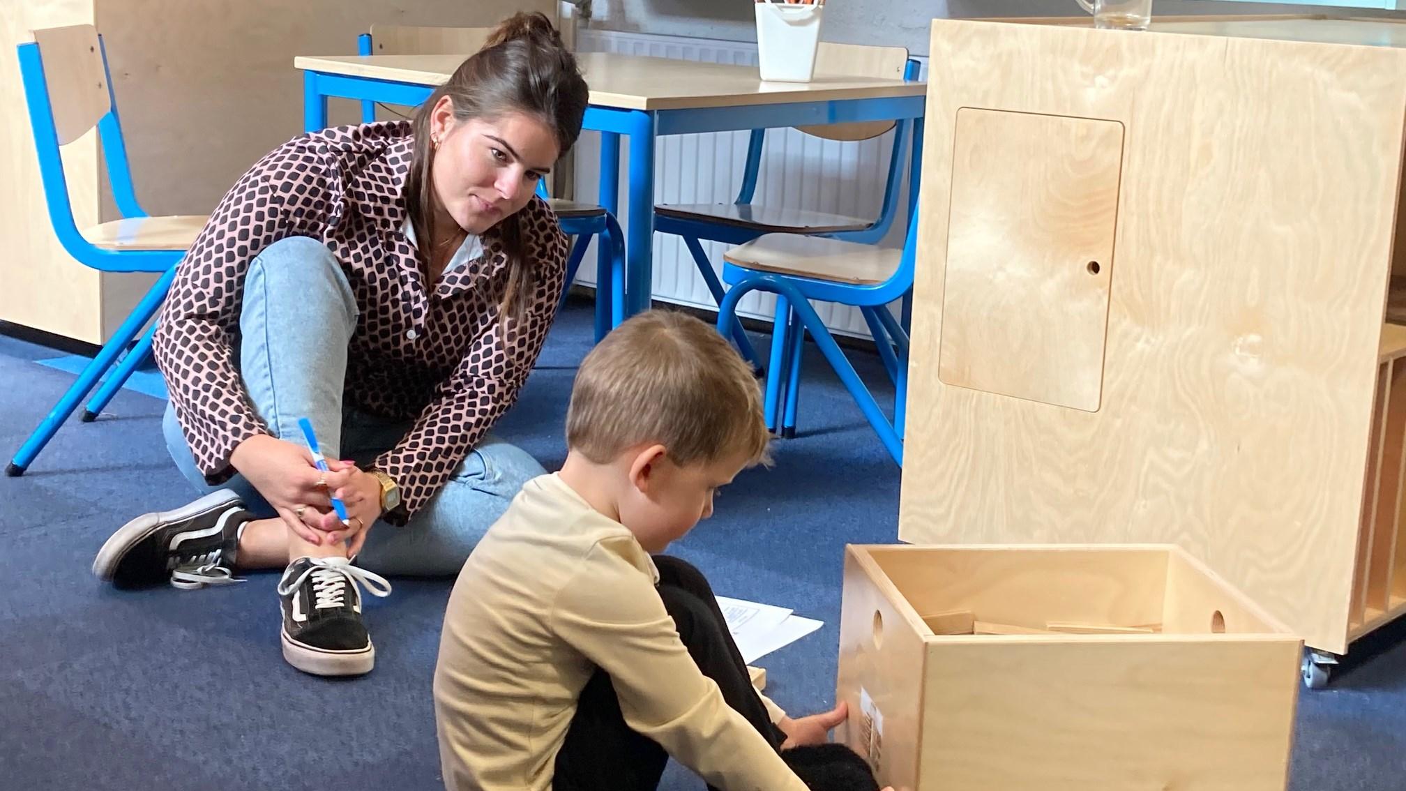 Een leerkracht helpt een kind met een activiteit in de klas van R.K. Basisschool WSKO Joannes in Naaldwijk.