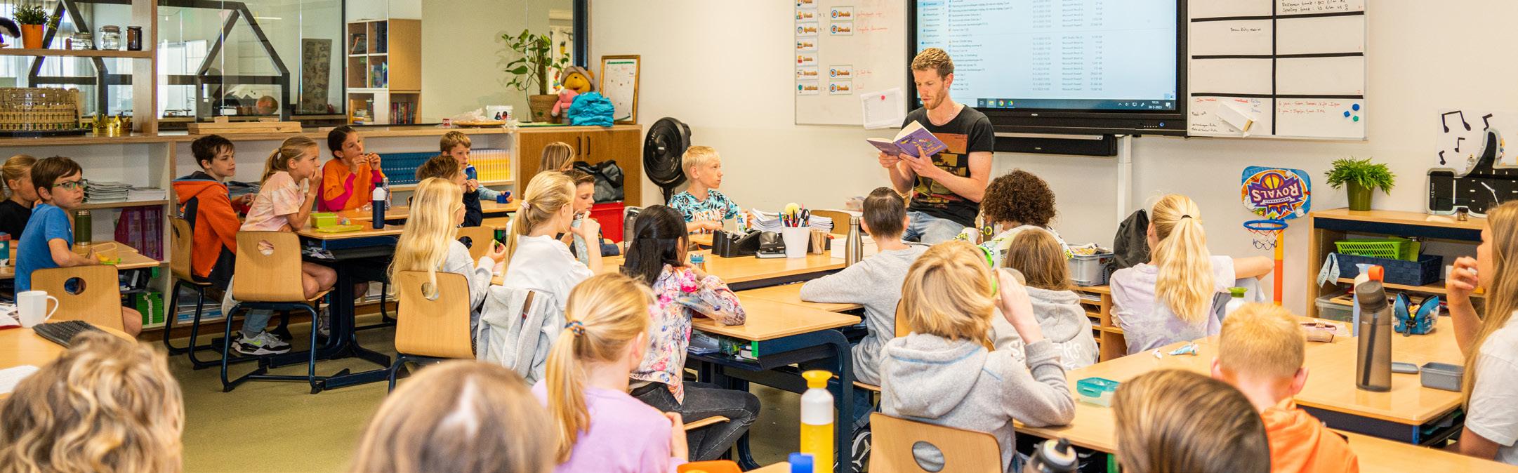 Een leerkracht leest voor aan leerlingen in de klas van de Fatimaschool in Rotterdam. Een leerkracht leest voor aan leerlingen in de klas van de Fatimaschool in Rotterdam.