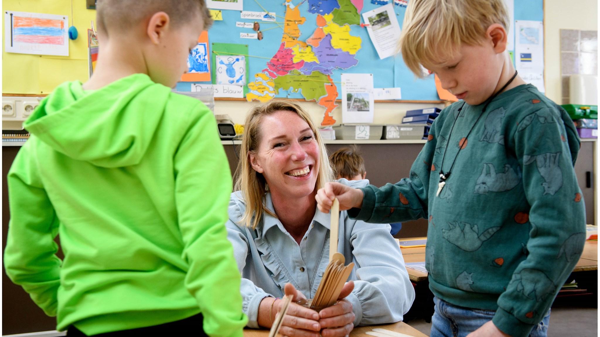 Een leerkracht, omringd door twee kinderen in de klas van Basisschool Bonifatius in Spanbroek, geniet van een interactieve activiteit met hen. Een leerkracht, omringd door twee kinderen in de klas van Basisschool Bonifatius in Spanbroek, geniet van een interactieve activiteit met hen.