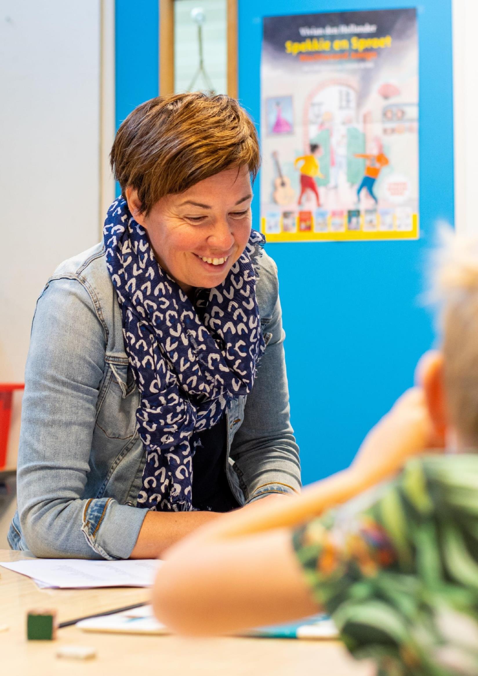 Een leerkracht van CBS De Adelaar in Wolvega legt met een glimlach iets uit aan een leerling. Een leerkracht van CBS De Adelaar in Wolvega legt met een glimlach iets uit aan een leerling.
