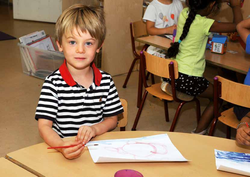 Een leerling aan de Amsterdam International Community School (AICS) in Amsterdam werkt creatief met verf aan een tafel. Een leerling aan de Amsterdam International Community School (AICS) in Amsterdam werkt creatief met verf aan een tafel.