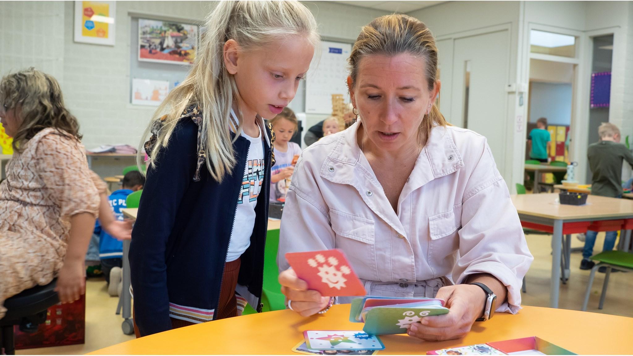 Een leerling en een leerkracht zijn bezig met kaarten in het klaslokaal van Openbare Basisschool De Triolier in Budel. Een leerling en een leerkracht zijn bezig met kaarten in het klaslokaal van Openbare Basisschool De Triolier in Budel.