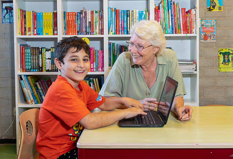 Een leerling en een lerares lachen terwijl ze samen werken aan een laptop in CBS Mozaïek in Rotterdam.