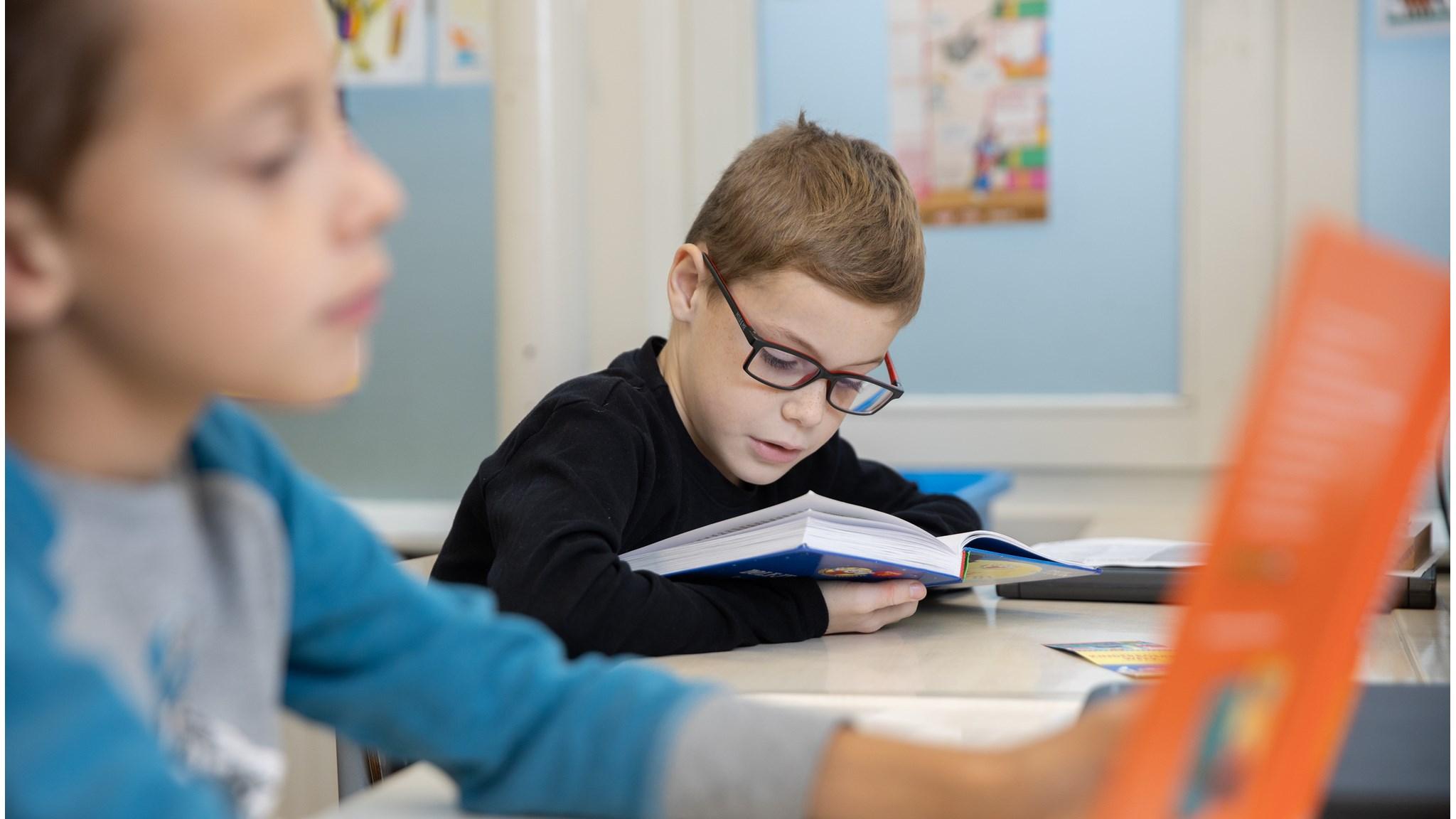 Een leerling leest aandachtig een boek in de klas van basisschool 'Ollie B Bommel' in Den Bommel. Een leerling leest aandachtig een boek in de klas van basisschool 'Ollie B Bommel' in Den Bommel.
