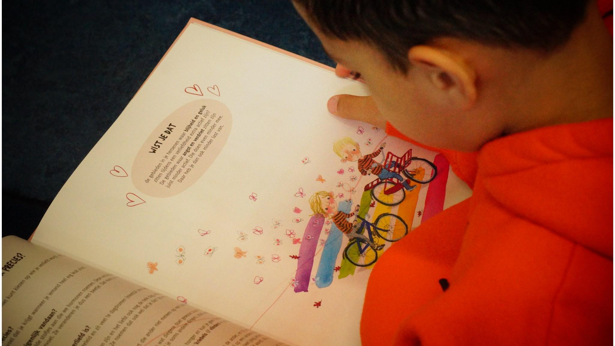Een leerling van Basisschool Anne Frank 6e Montessori-School in Amsterdam leest een kleurrijk boek. Een leerling van Basisschool Anne Frank 6e Montessori-School in Amsterdam leest een kleurrijk boek.
