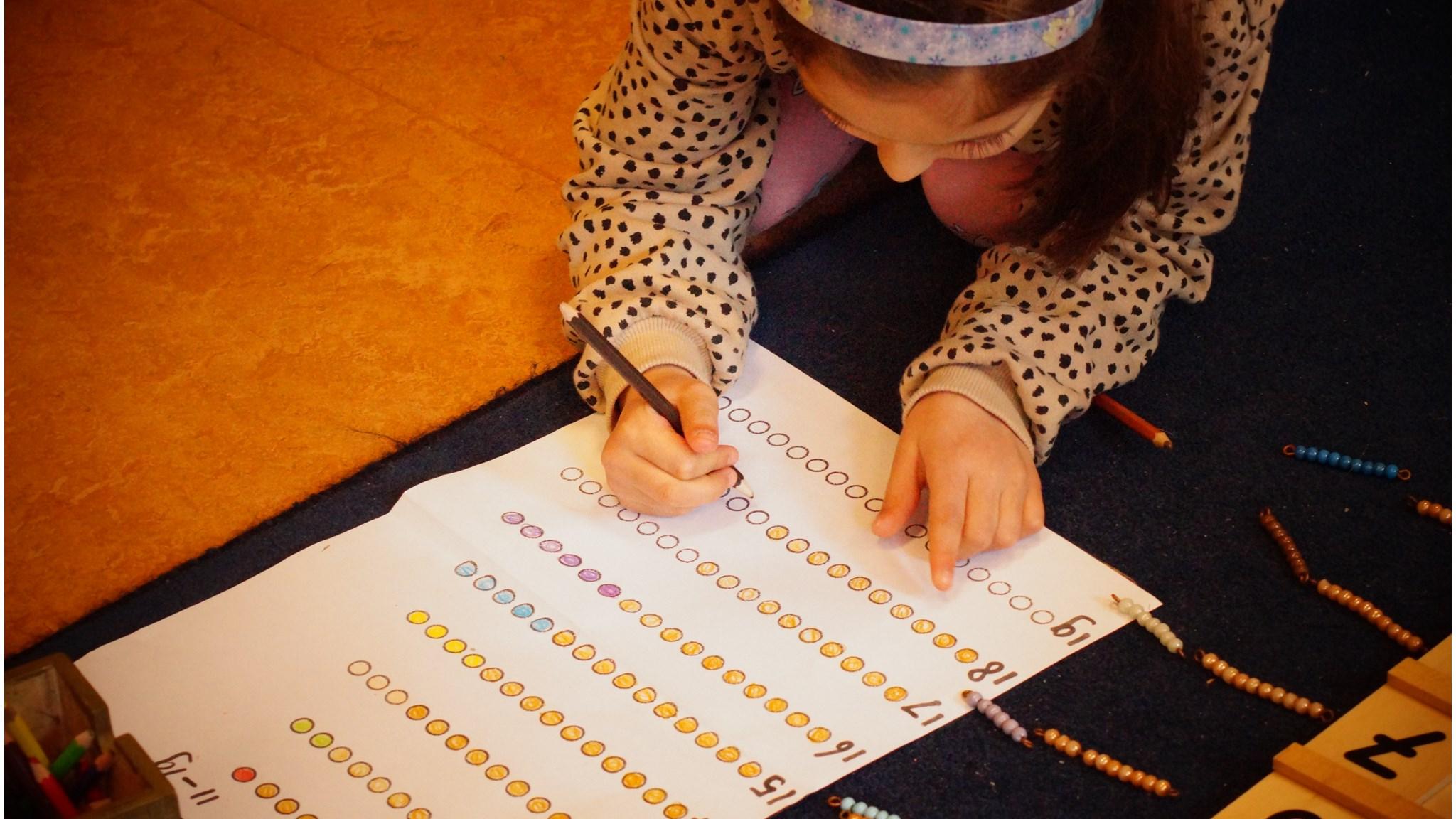 Een leerling van Basisschool Anne Frank 6e Montessori-School in Amsterdam maakt haar werk op een kleurig werkblad. Een leerling van Basisschool Anne Frank 6e Montessori-School in Amsterdam maakt haar werk op een kleurig werkblad.