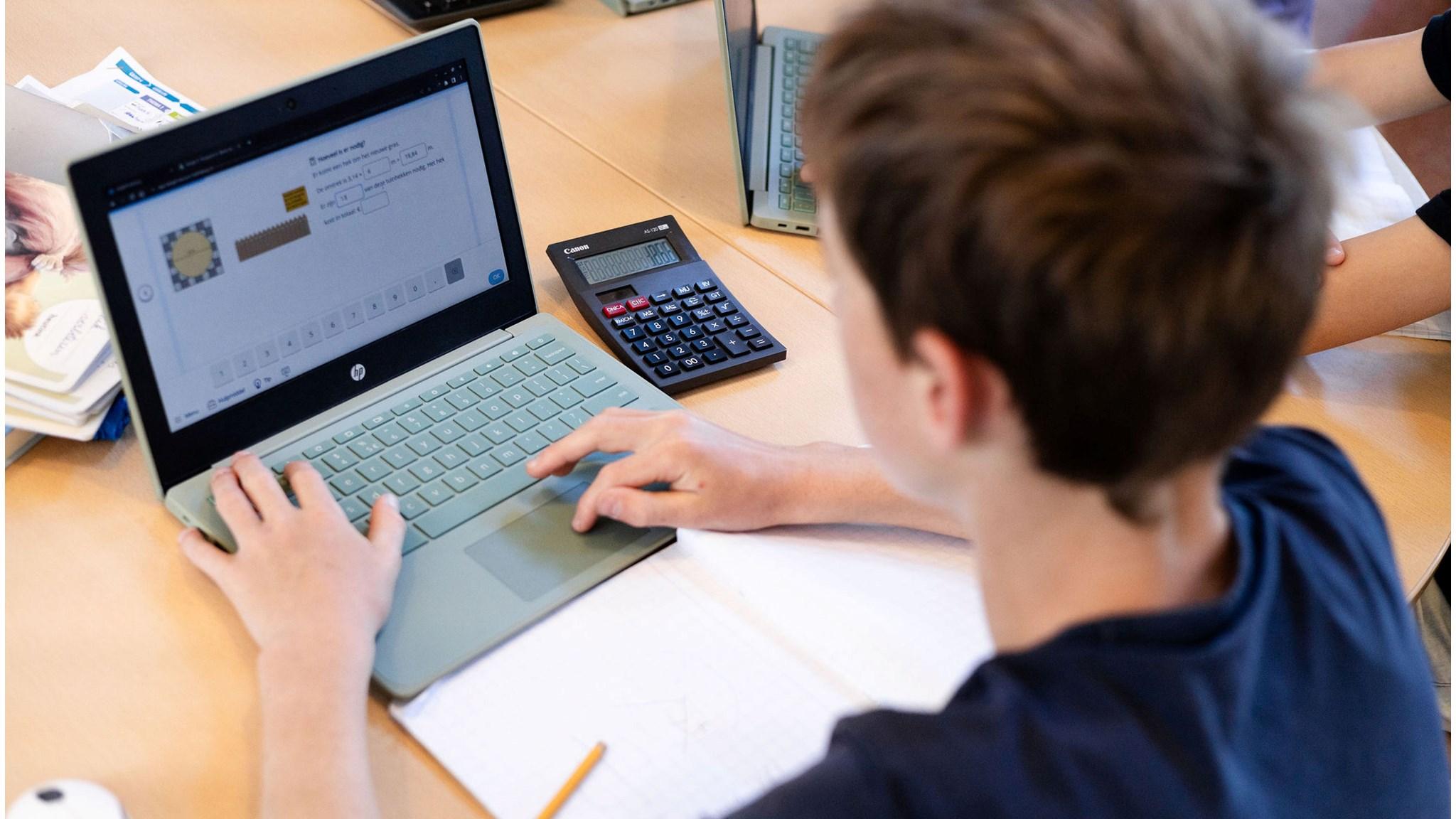 Een leerling van Basisschool De Boogerd in 't Goy werkt aan zijn laptop met een rekenmachine naast zich. Een leerling van Basisschool De Boogerd in 't Goy werkt aan zijn laptop met een rekenmachine naast zich.