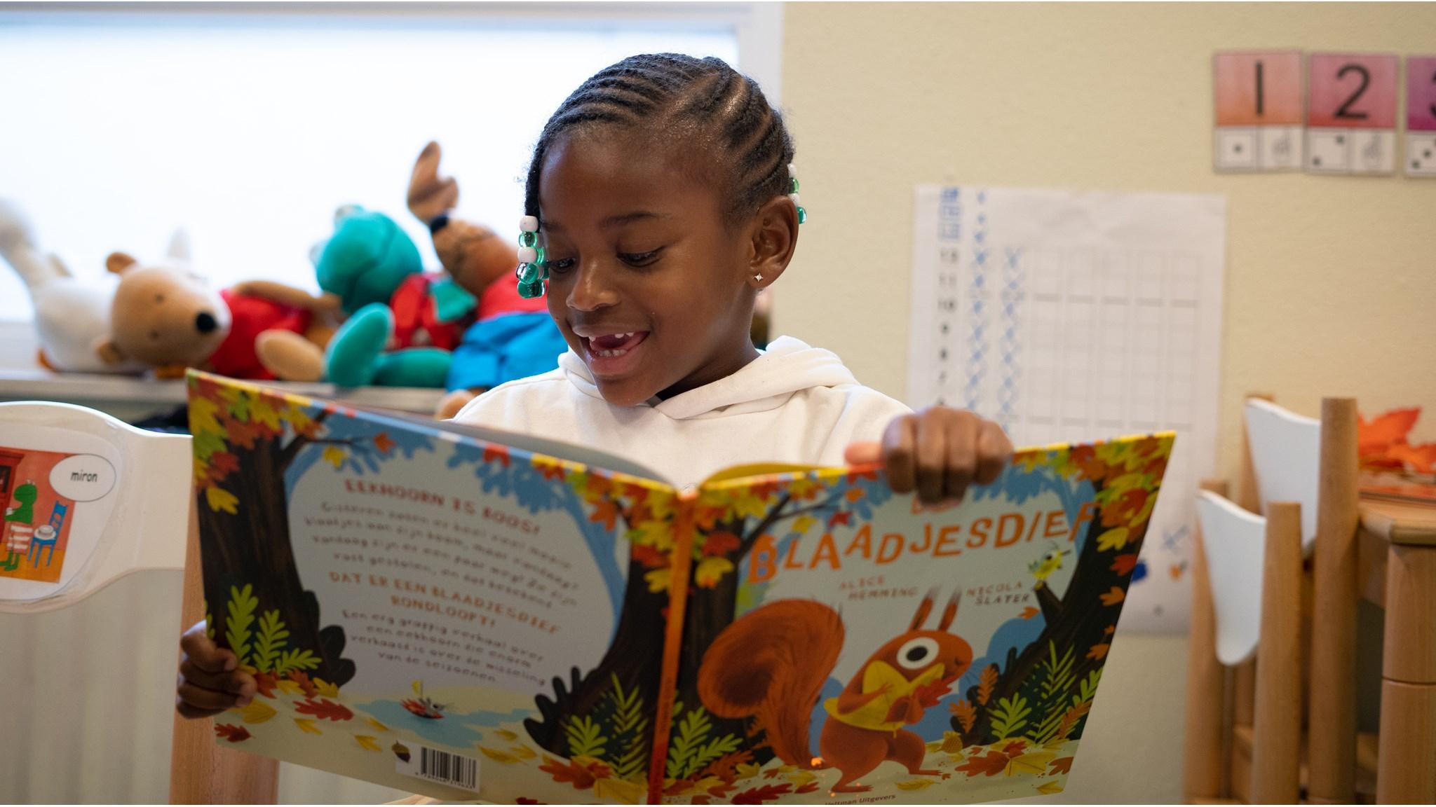 Een leerling van Basisschool de Olijfboom in Almere leest enthousiast een boek met de titel "Blaadjesdie". Een leerling van Basisschool de Olijfboom in Almere leest enthousiast een boek met de titel "Blaadjesdie".