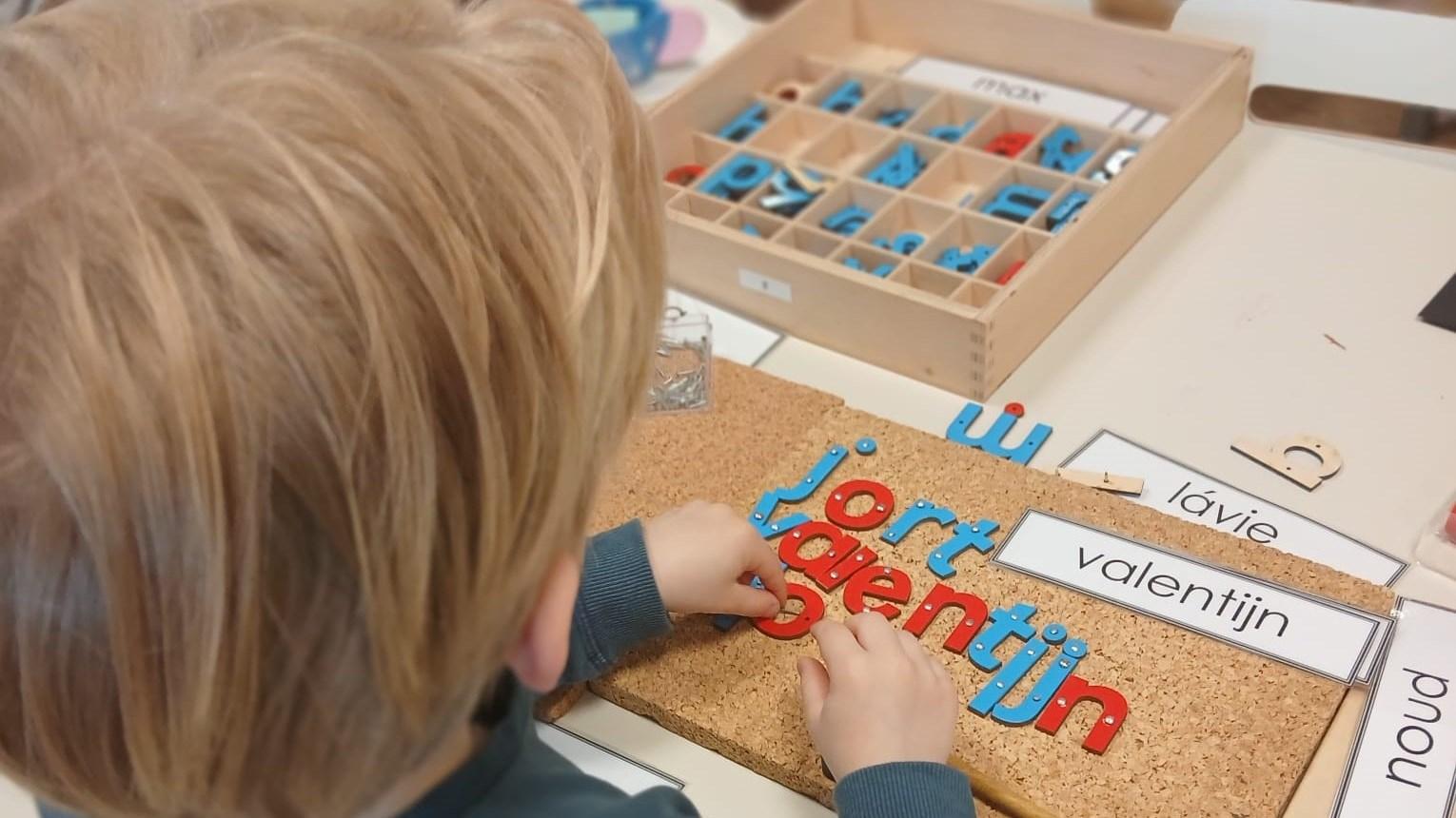 Een leerling van Basisschool Sint Tarcisius in Heerlen maakt woorden met letters op een kurkplaat. Een leerling van Basisschool Sint Tarcisius in Heerlen maakt woorden met letters op een kurkplaat.
