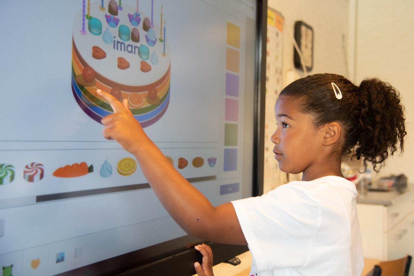 Een leerling van Basisschool Wisperweide in Weesp wijst naar een digitale afbeelding van een taart op een interactief bord. Een leerling van Basisschool Wisperweide in Weesp wijst naar een digitale afbeelding van een taart op een interactief bord.