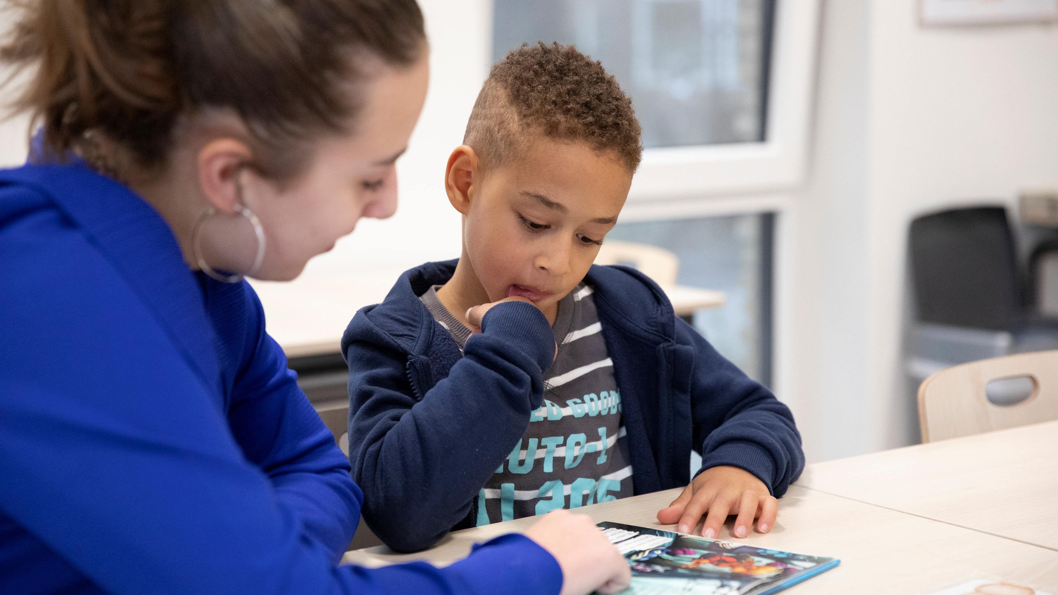 Een leerling van cbs Marimba in Spijkenisse leest aandachtig met een begeleider tijdens een lesactiviteit. Een leerling van cbs Marimba in Spijkenisse leest aandachtig met een begeleider tijdens een lesactiviteit.