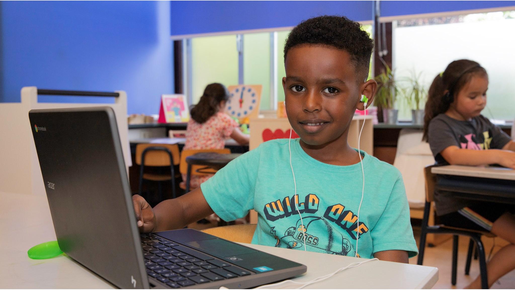 Een leerling van De Antoniusschool in Nieuw-Vennep werkt enthousiast aan een laptop in de klas. Een leerling van De Antoniusschool in Nieuw-Vennep werkt enthousiast aan een laptop in de klas.