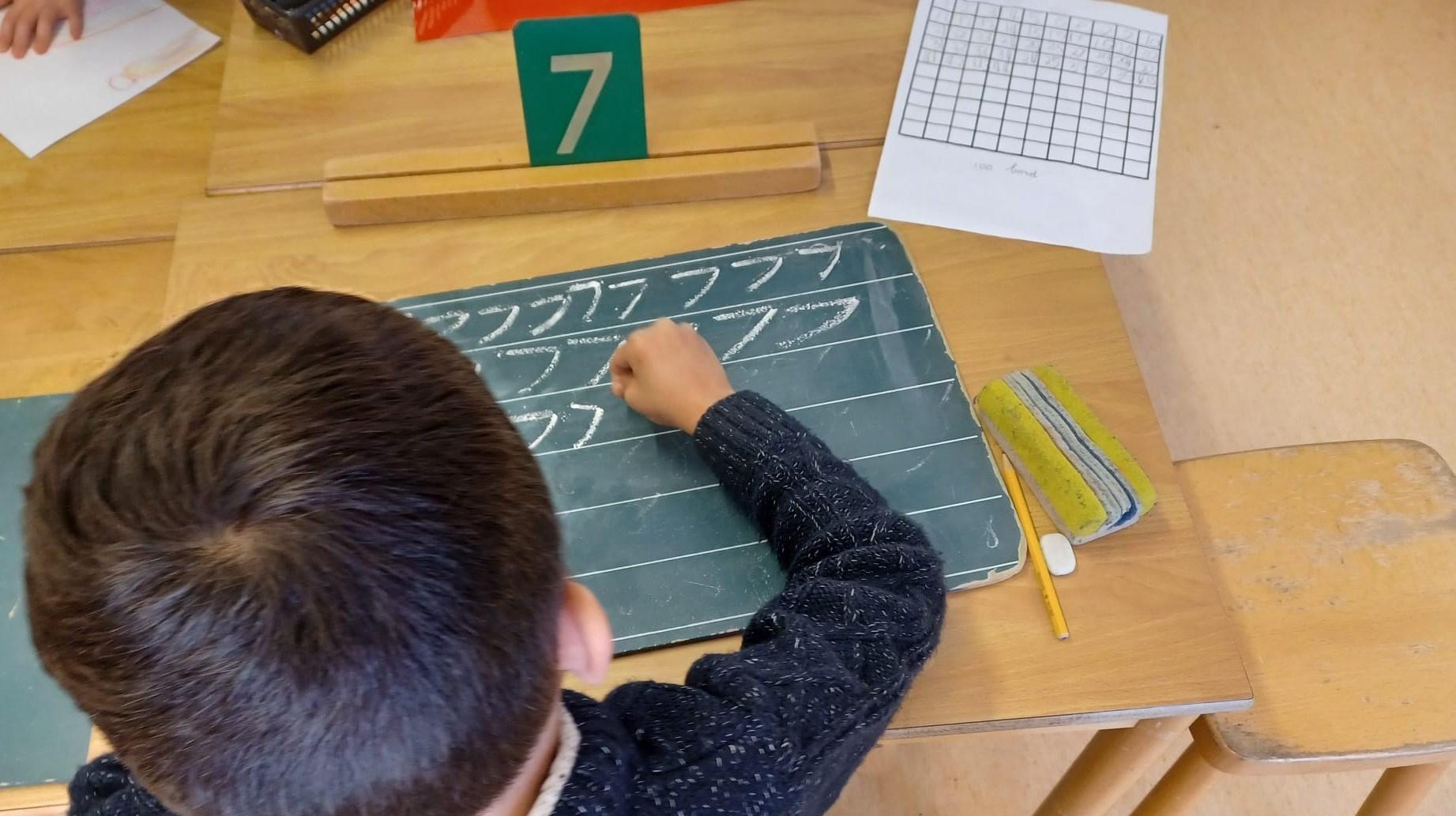 Een leerling van de Boerhaave School in Groningen is bezig met schrijven op een schoolbord. Een leerling van de Boerhaave School in Groningen is bezig met schrijven op een schoolbord.
