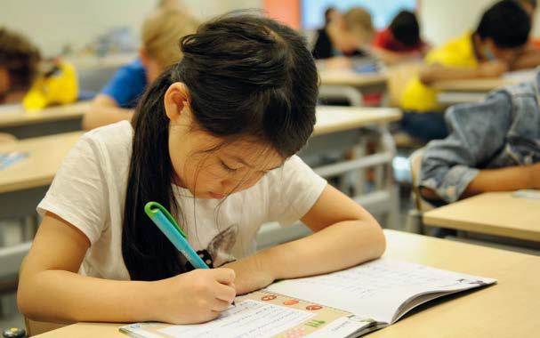 Een leerling van de Lorentzschool in Leiden is geconcentreerd aan het schrijven in de klas. Een leerling van de Lorentzschool in Leiden is geconcentreerd aan het schrijven in de klas.