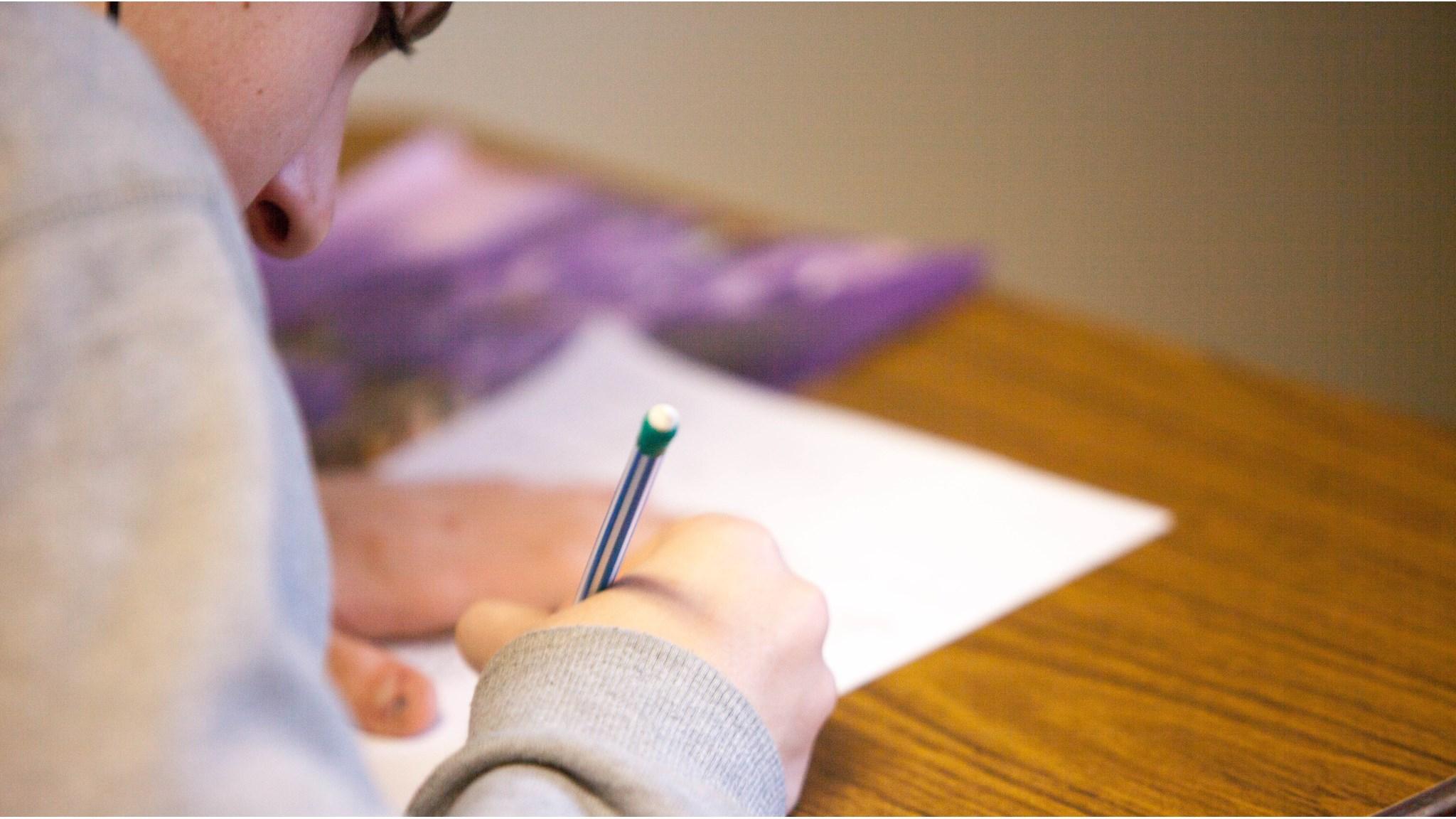 Een leerling van de Oranjeschool voor Basisonderwijs in Rotterdam werkt geconcentreerd aan een schriftelijke opdracht.