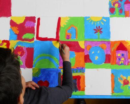 Een leerling van de Parkschool in Delft schildert kleurrijke vakken op een groot doek tijdens een creatieve activiteit. Een leerling van de Parkschool in Delft schildert kleurrijke vakken op een groot doek tijdens een creatieve activiteit.