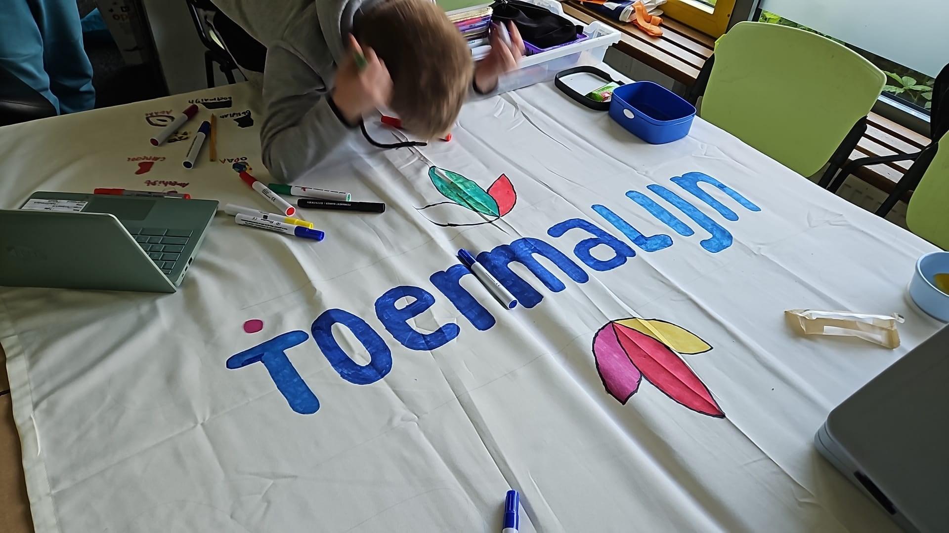 Een leerling van de School voor Speciaal Basisonderwijs Toermalijn in Zaltbommel werkt aan een kleurrijke banner. Een leerling van de School voor Speciaal Basisonderwijs Toermalijn in Zaltbommel werkt aan een kleurrijke banner.