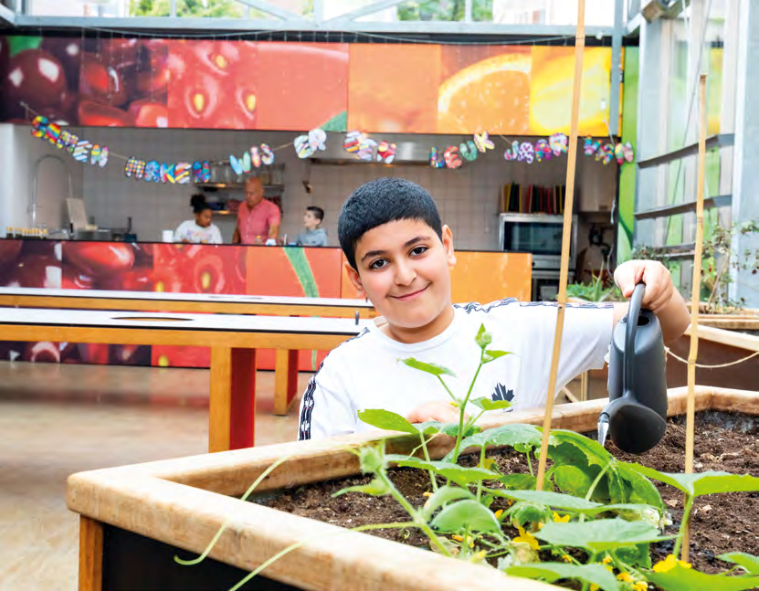Een leerling van De Springplank in Huizen water geeft aan planten in de schooltuin. Een leerling van De Springplank in Huizen water geeft aan planten in de schooltuin.