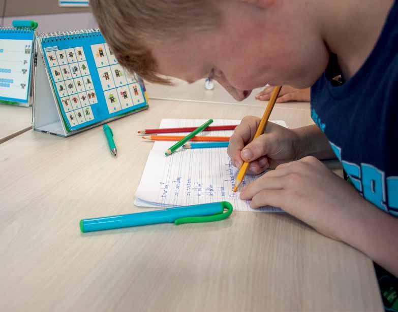 Een leerling van De Vlindertuin in Voorthuizen schrijft in zijn schrift met kleurrijke stiften. Een leerling van De Vlindertuin in Voorthuizen schrijft in zijn schrift met kleurrijke stiften.