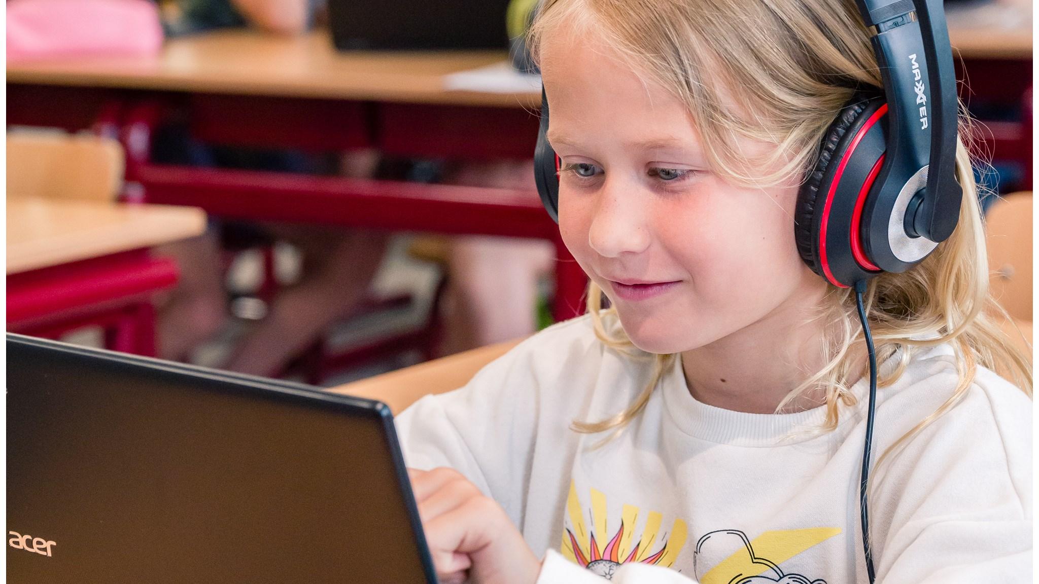 Een leerling van De Wijde Blik in Kamerik gebruikt een laptop met koptelefoon in de klas. Een leerling van De Wijde Blik in Kamerik gebruikt een laptop met koptelefoon in de klas.