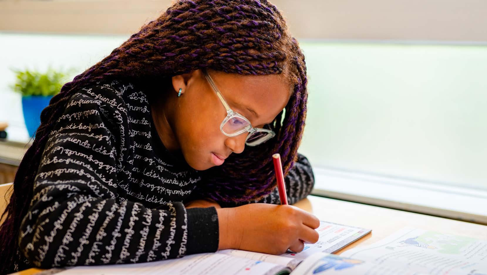 Een leerling van De Zuidster in Zwolle is geconcentreerd aan het werk in een schoolboek. Een leerling van De Zuidster in Zwolle is geconcentreerd aan het werk in een schoolboek.