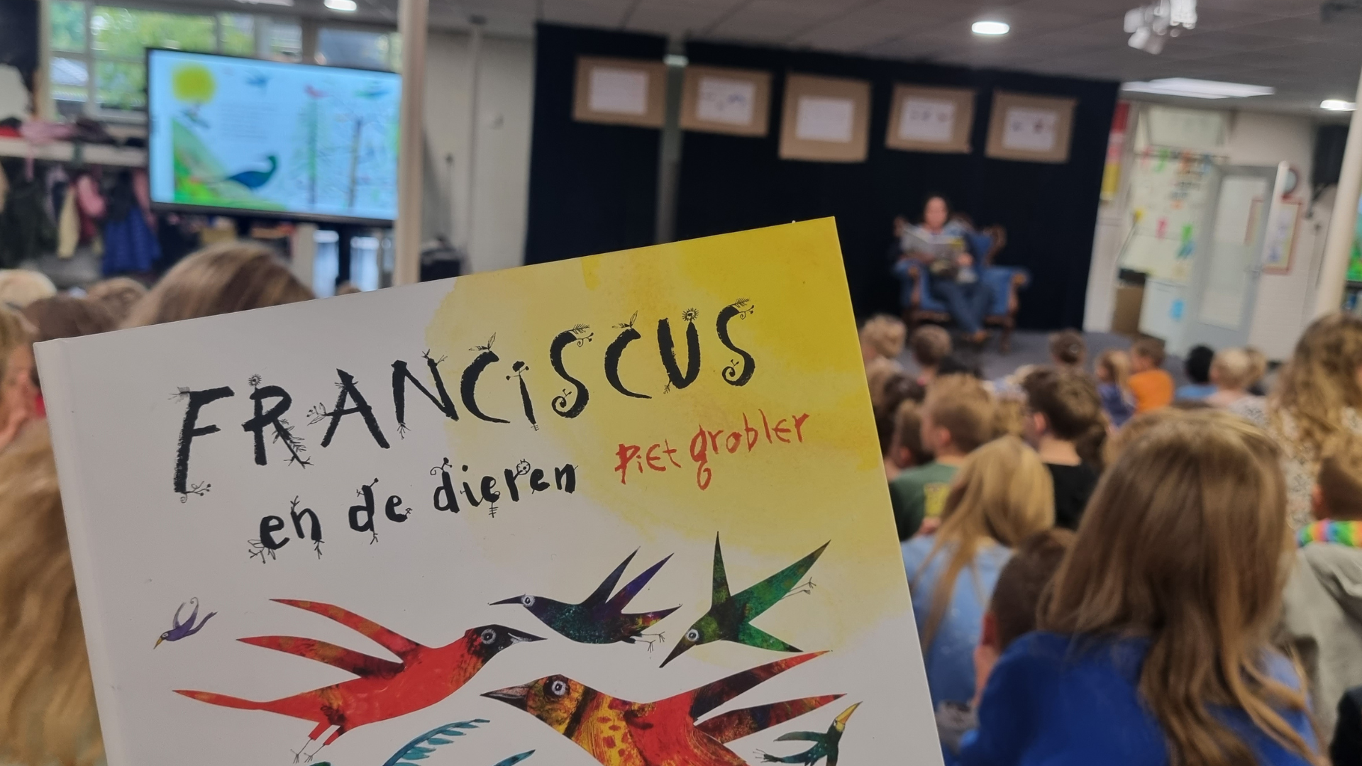 Een leerling van Jenaplanschool St. Franciscus in Nunspeet luistert naar een verhaal terwijl een boek met de titel "Franciscus en de dieren" wordt getoond. Een leerling van Jenaplanschool St. Franciscus in Nunspeet luistert naar een verhaal terwijl een boek met de titel "Franciscus en de dieren" wordt getoond.