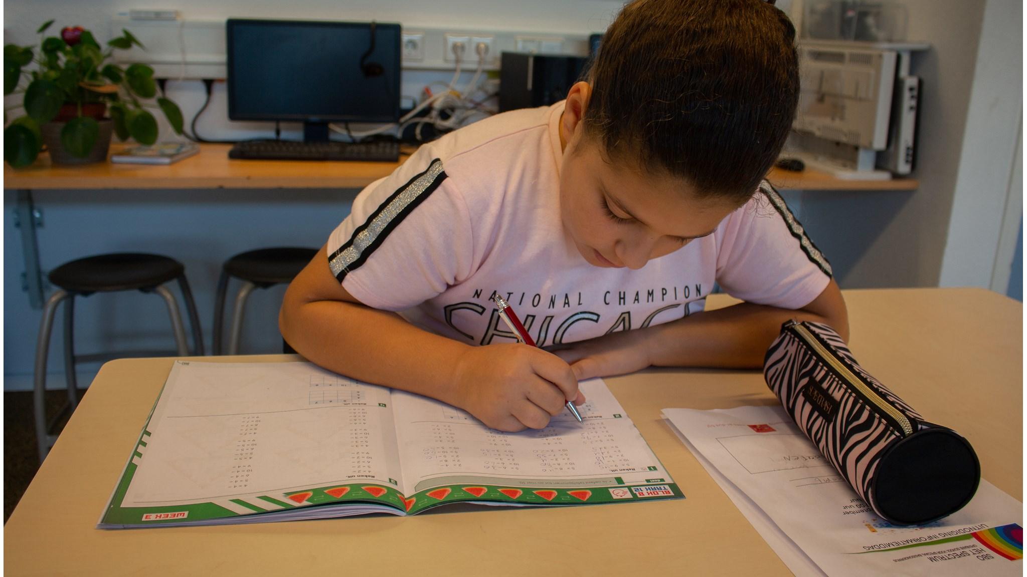 Een leerling van Kindcentrum Montessori Hoorn is bezig met huiswerk aan een tafel. Een leerling van Kindcentrum Montessori Hoorn is bezig met huiswerk aan een tafel.